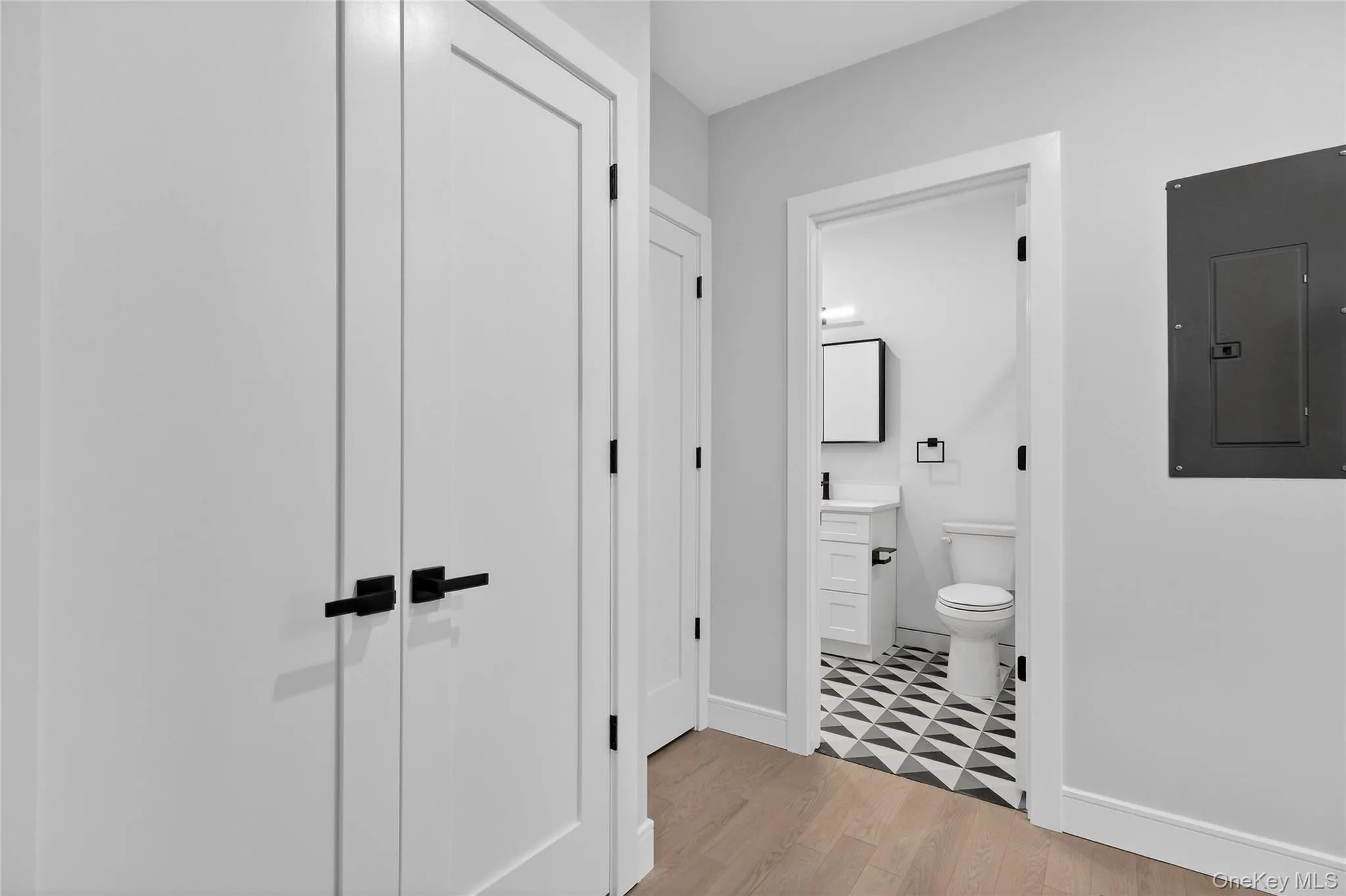 Bathroom featuring electric panel, vanity, and light wood finished floors Bathroom featuring electric panel, vanity, and light wood finished floors