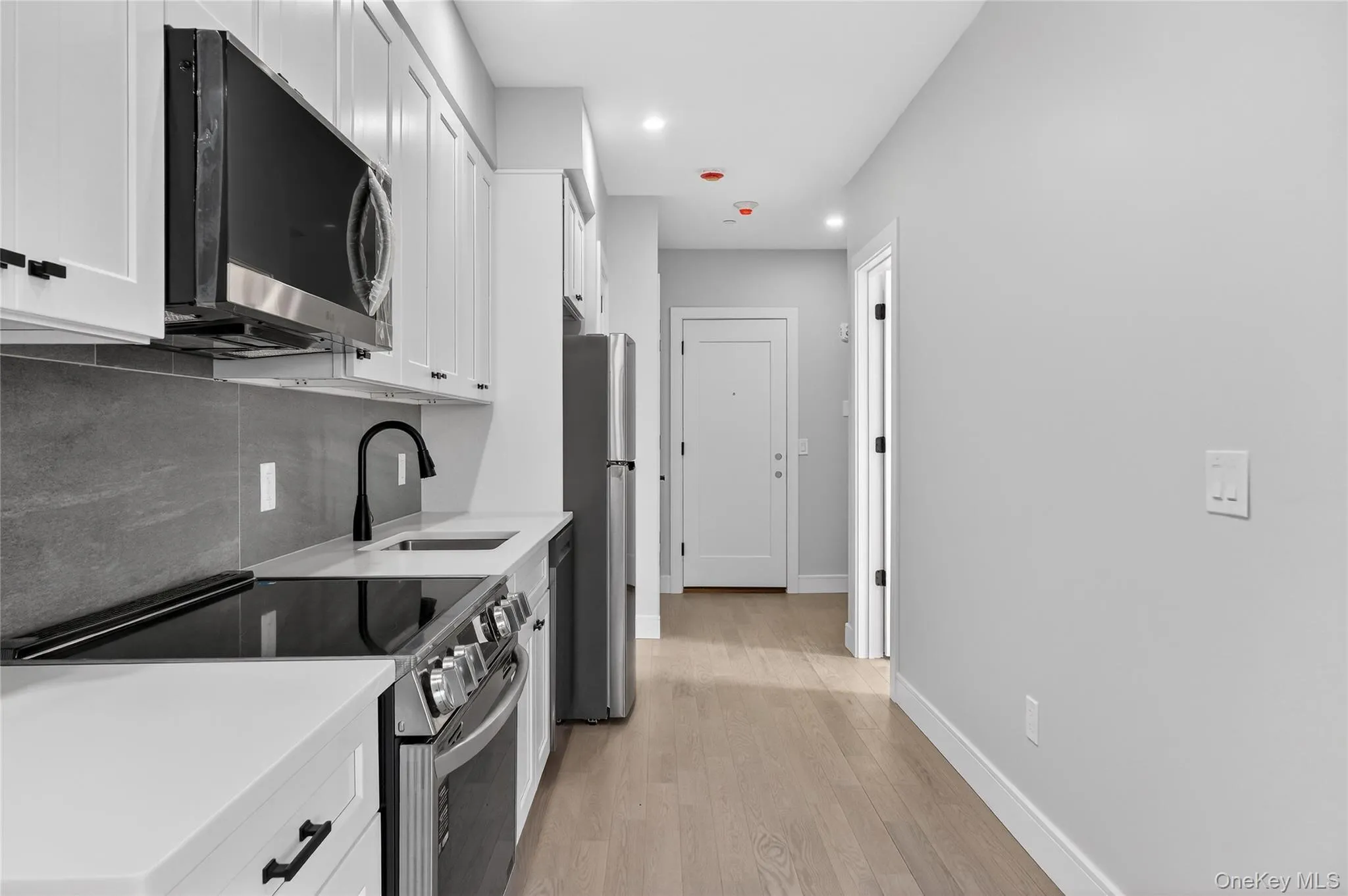 Kitchen featuring stainless steel appliances, white cabinets, decorative backsplash, light wood-type flooring, and recessed lighting Kitchen featuring stainless steel appliances, white cabinets, decorative backsplash, light wood-type flooring, and recessed lighting