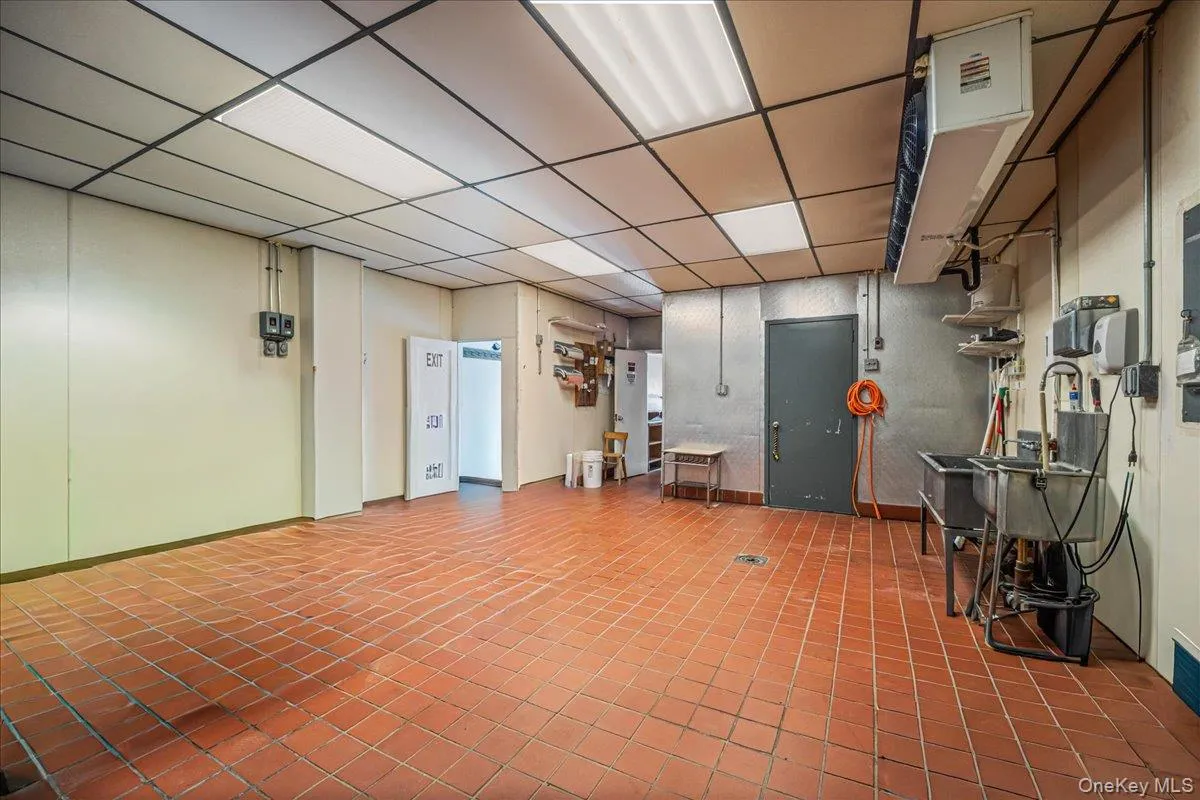 Below grade area featuring a heating unit, a drop ceiling, and tile patterned flooring Below grade area featuring a heating unit, a drop ceiling, and tile patterned flooring