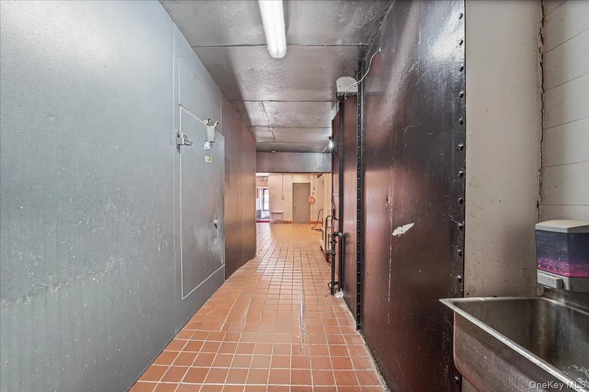 Hallway featuring light tile patterned flooring and a sink Hallway featuring light tile patterned flooring and a sink