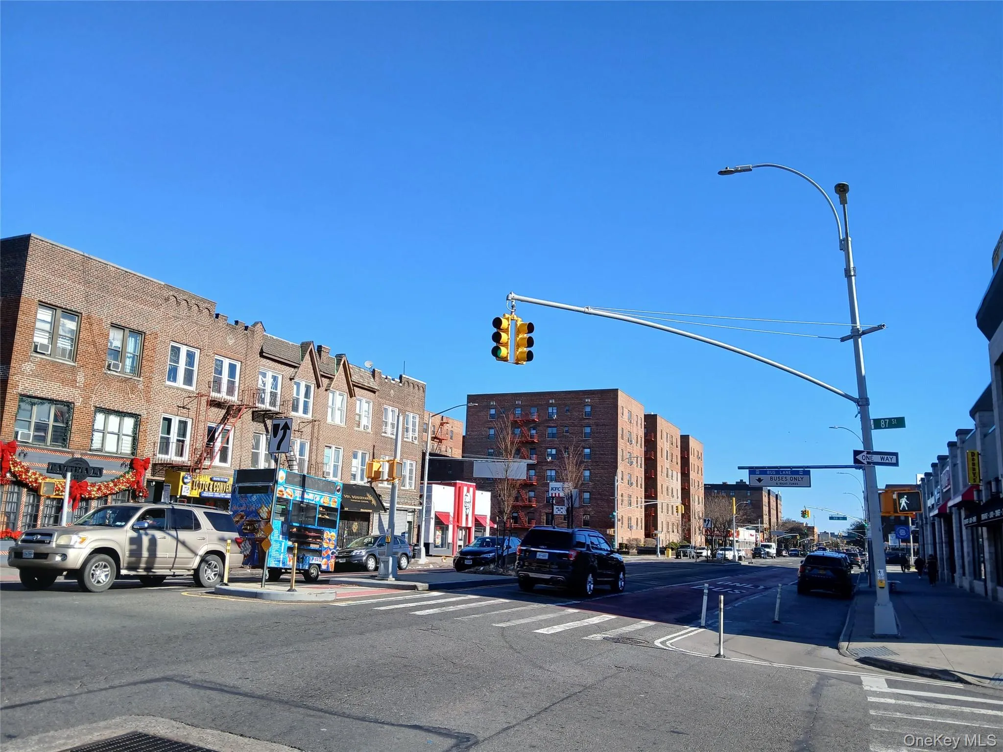 View of asphalt road featuring traffic lights, sidewalks, street lighting, and curbs View of asphalt road featuring traffic lights, sidewalks, street lighting, and curbs