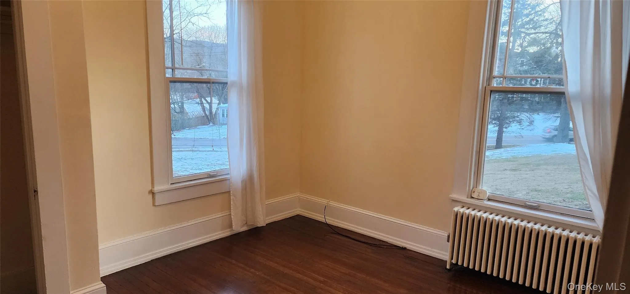 Bedroom with radiator, dark wood-style flooring, and healthy amount of natural light Bedroom with radiator, dark wood-style flooring, and healthy amount of natural light