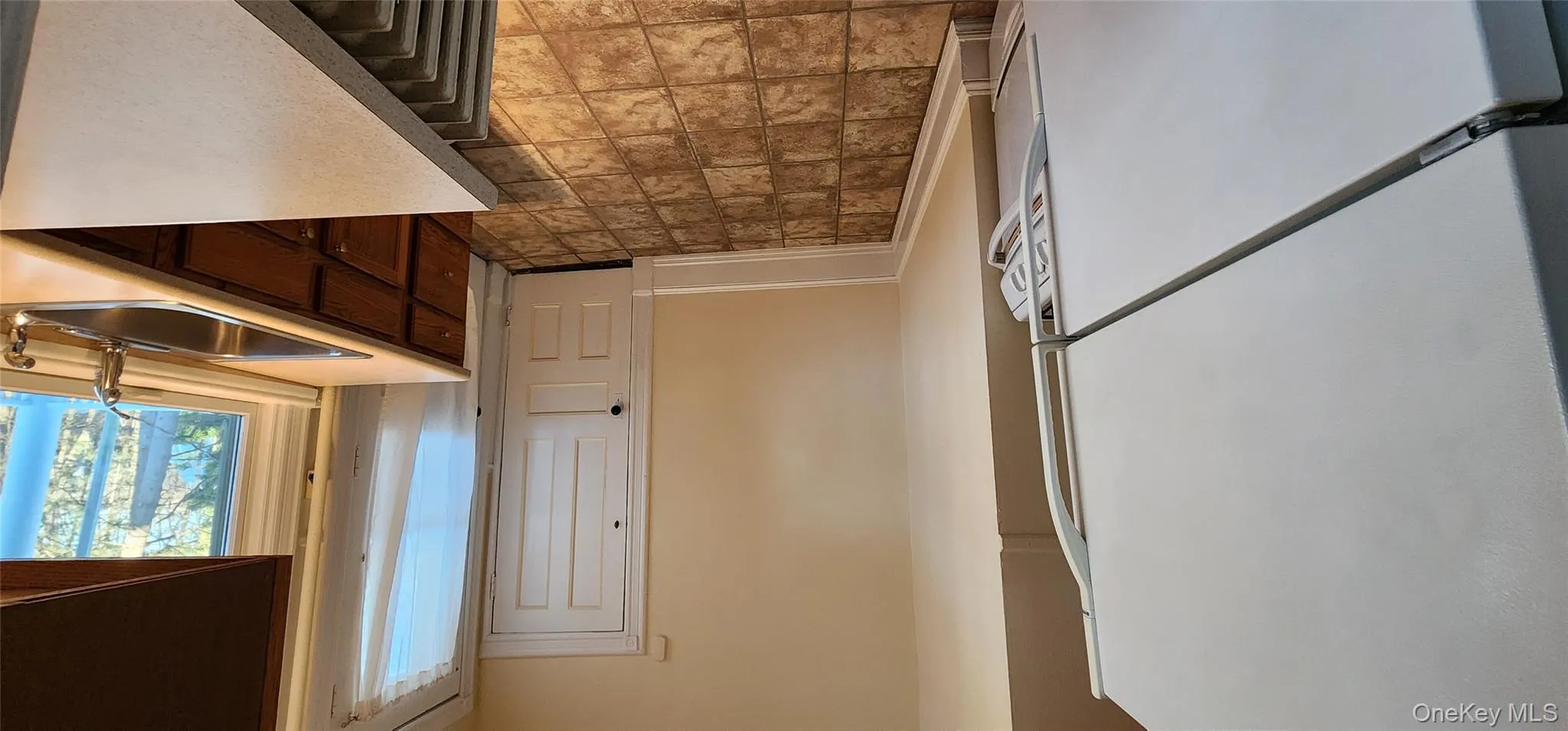 Kitchen featuring fridge, light countertops, stone finish floors, stove, and dark brown cabinets Kitchen featuring fridge, light countertops, stone finish floors, stove, and dark brown cabinets