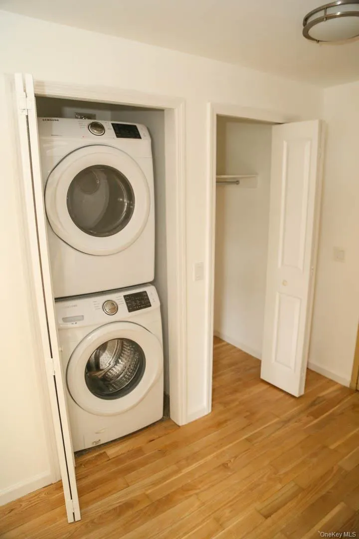 Washroom with stacked washer / dryer and light wood-type flooring Washroom with stacked washer / dryer and light wood-type flooring