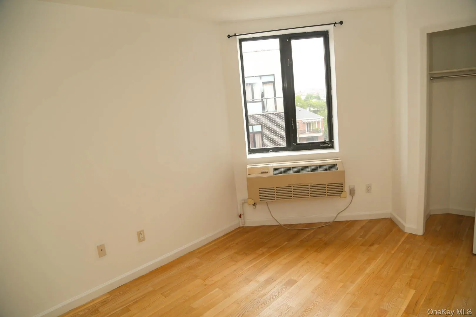 Unfurnished bedroom featuring light wood-style flooring, radiator, and a closet Unfurnished bedroom featuring light wood-style flooring, radiator, and a closet