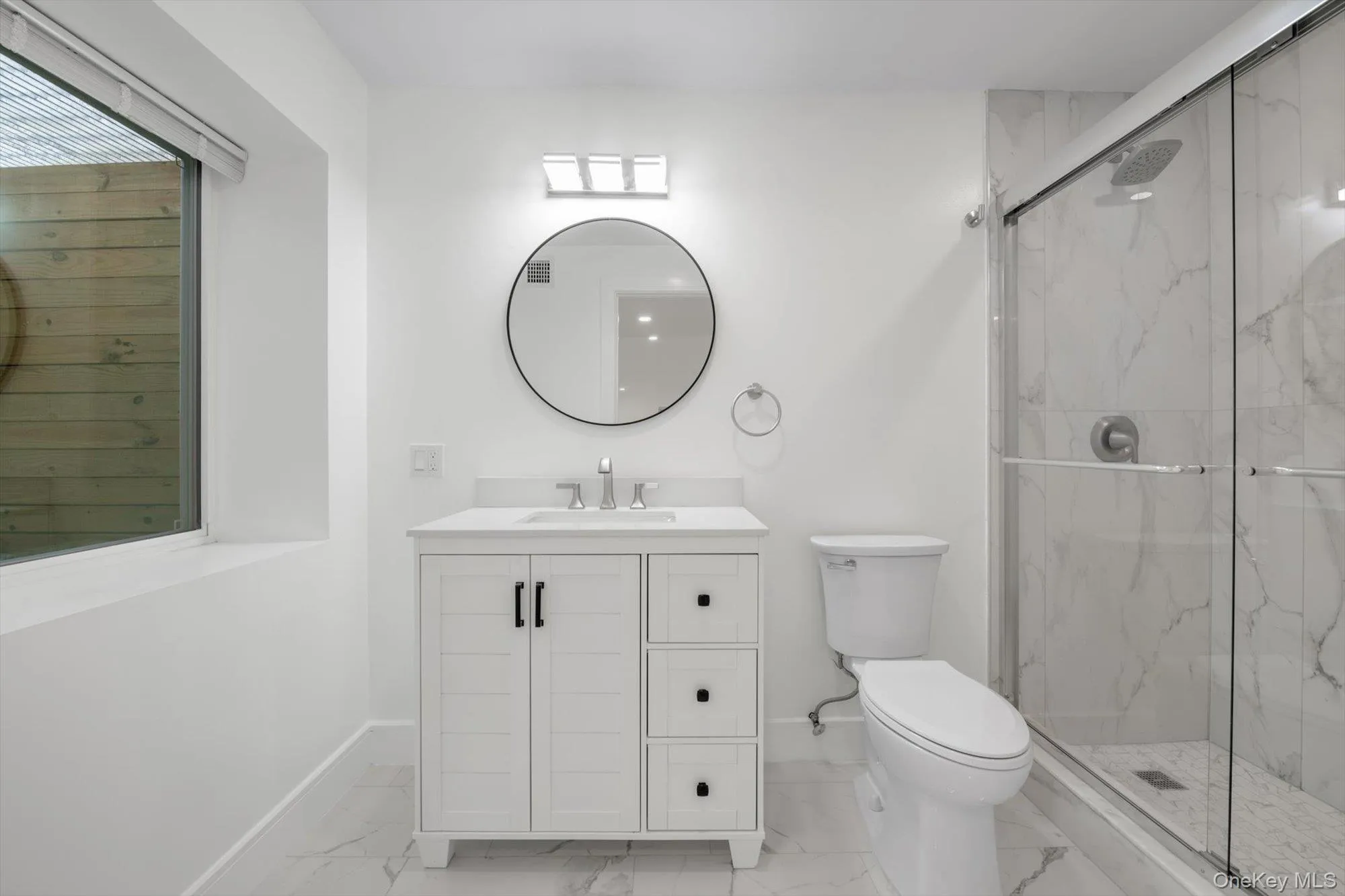 Bathroom with light marble finish floors, a marble finish shower, and vanity Bathroom with light marble finish floors, a marble finish shower, and vanity