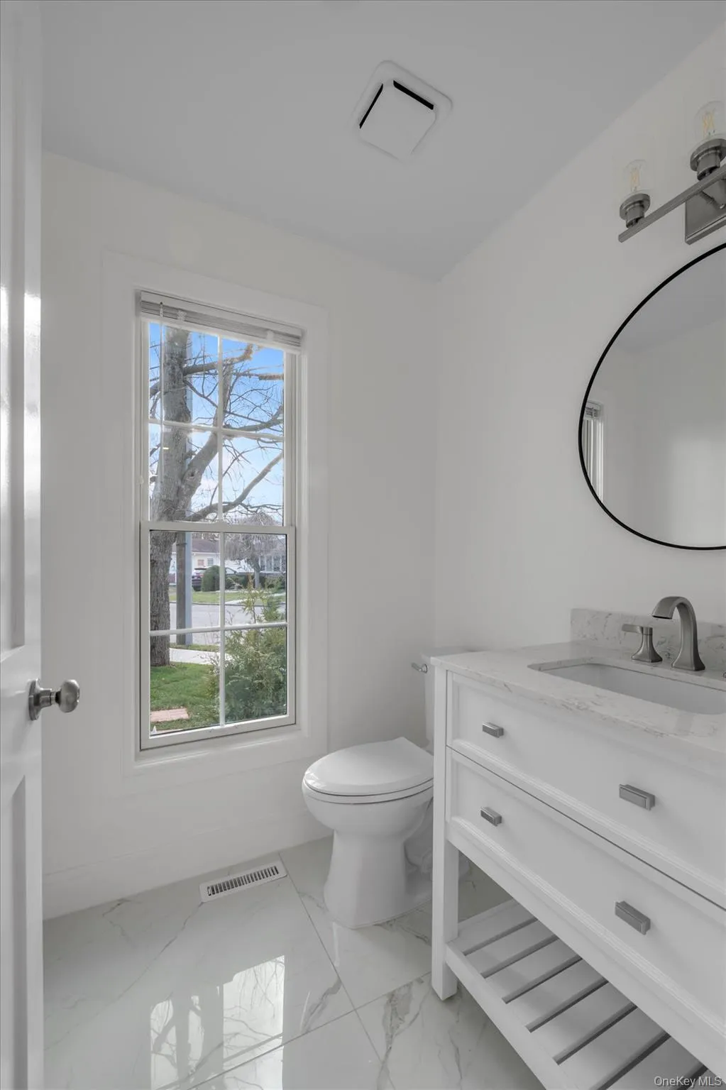 Half bath featuring vanity and light marble finish flooring Half bath featuring vanity and light marble finish flooring