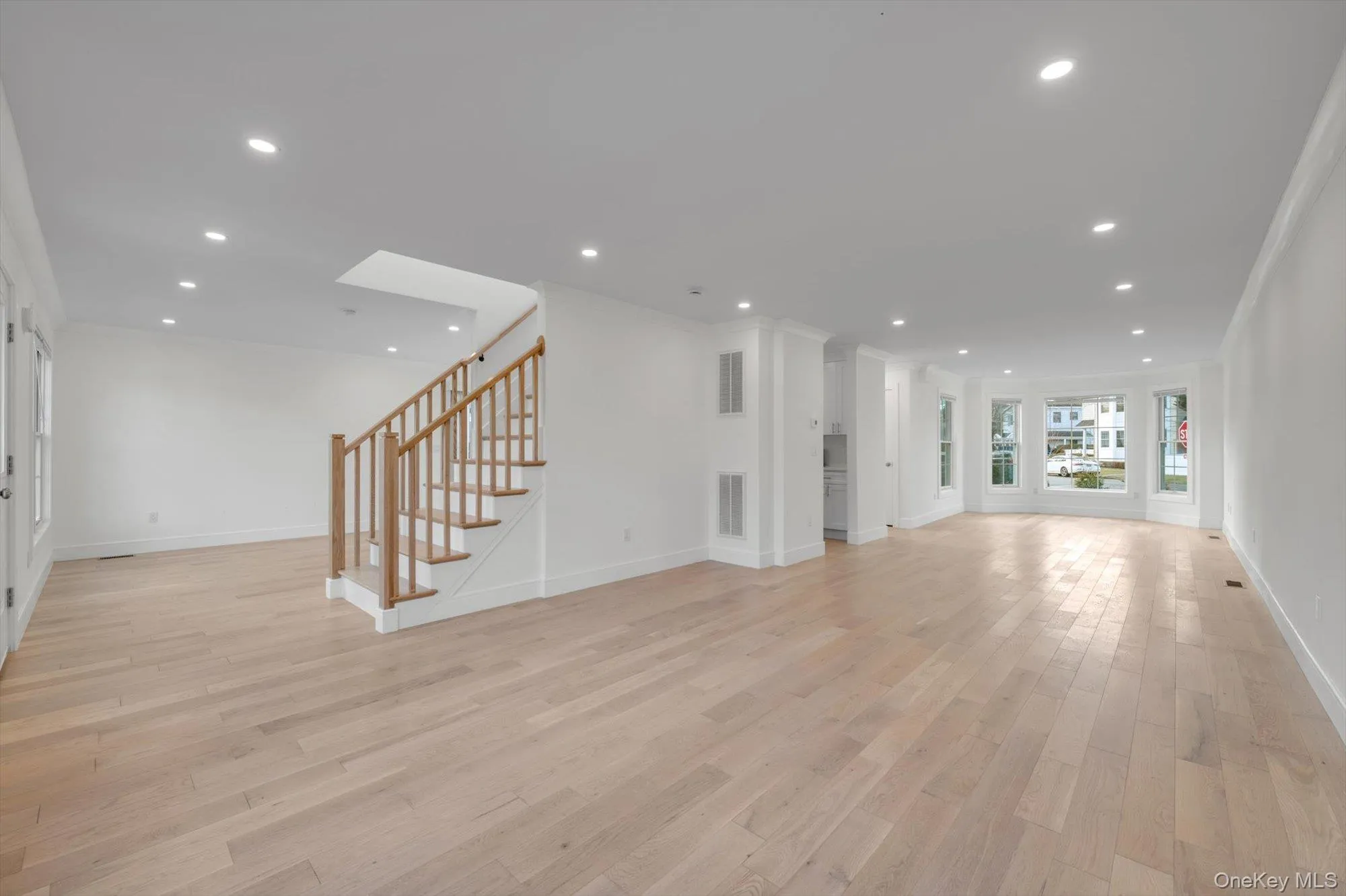 Unfurnished living room featuring light wood-style floors, crown molding, recessed lighting, stairway, and a skylight Unfurnished living room featuring light wood-style floors, crown molding, recessed lighting, stairway, and a skylight