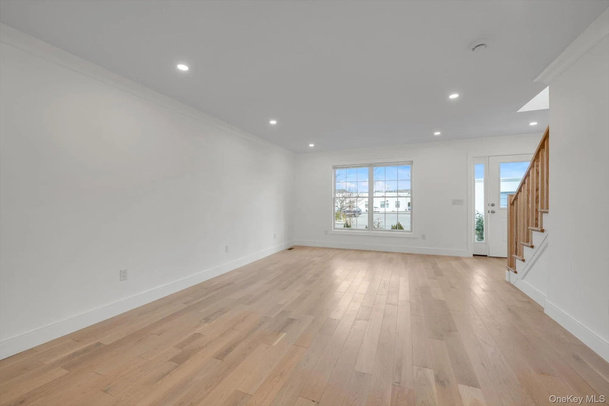 Unfurnished living room with recessed lighting, light wood finished floors, stairs, and crown molding Unfurnished living room with recessed lighting, light wood finished floors, stairs, and crown molding