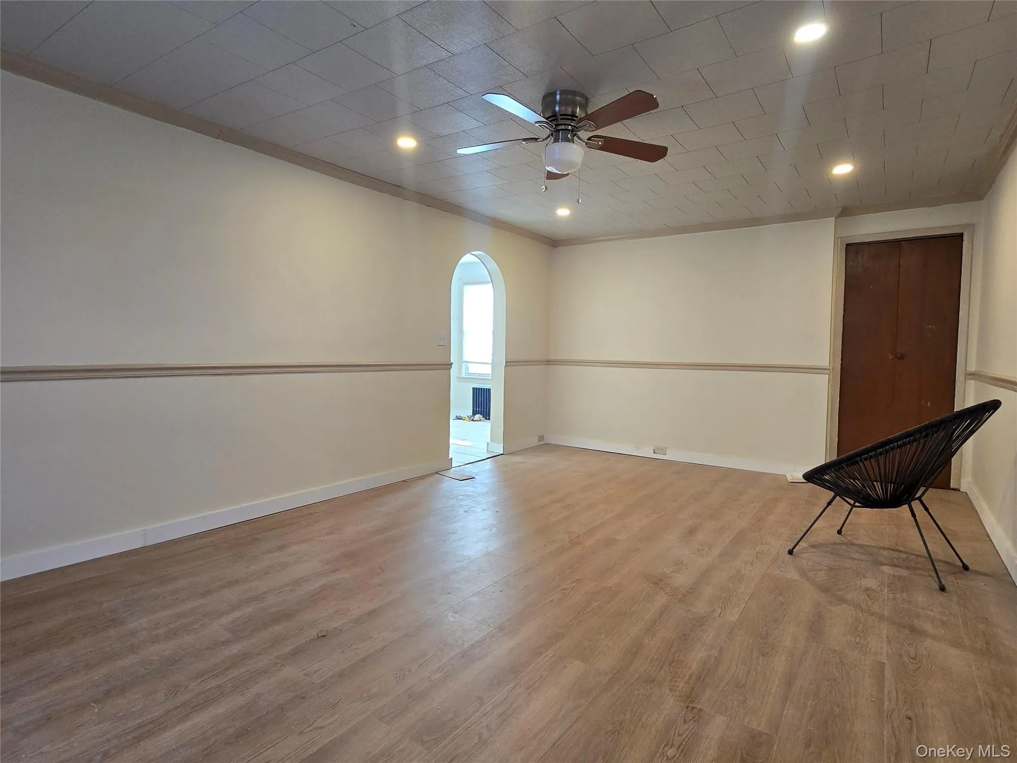 Unfurnished room with arched walkways, wood finished floors, recessed lighting, ceiling fan, and ornamental molding Unfurnished room with arched walkways, wood finished floors, recessed lighting, ceiling fan, and ornamental molding
