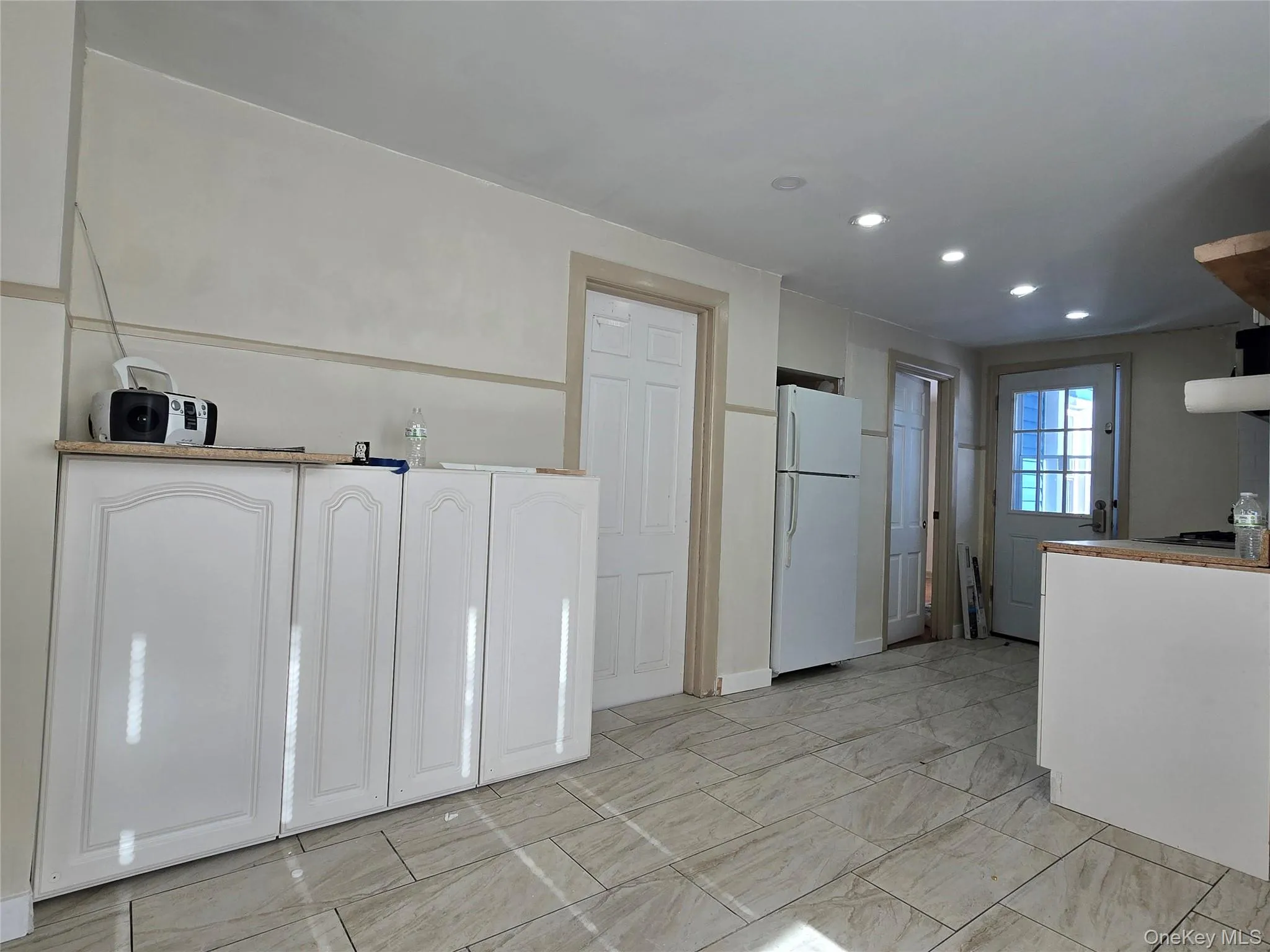 Kitchen featuring white cabinets, freestanding refrigerator, and recessed lighting Kitchen featuring white cabinets, freestanding refrigerator, and recessed lighting