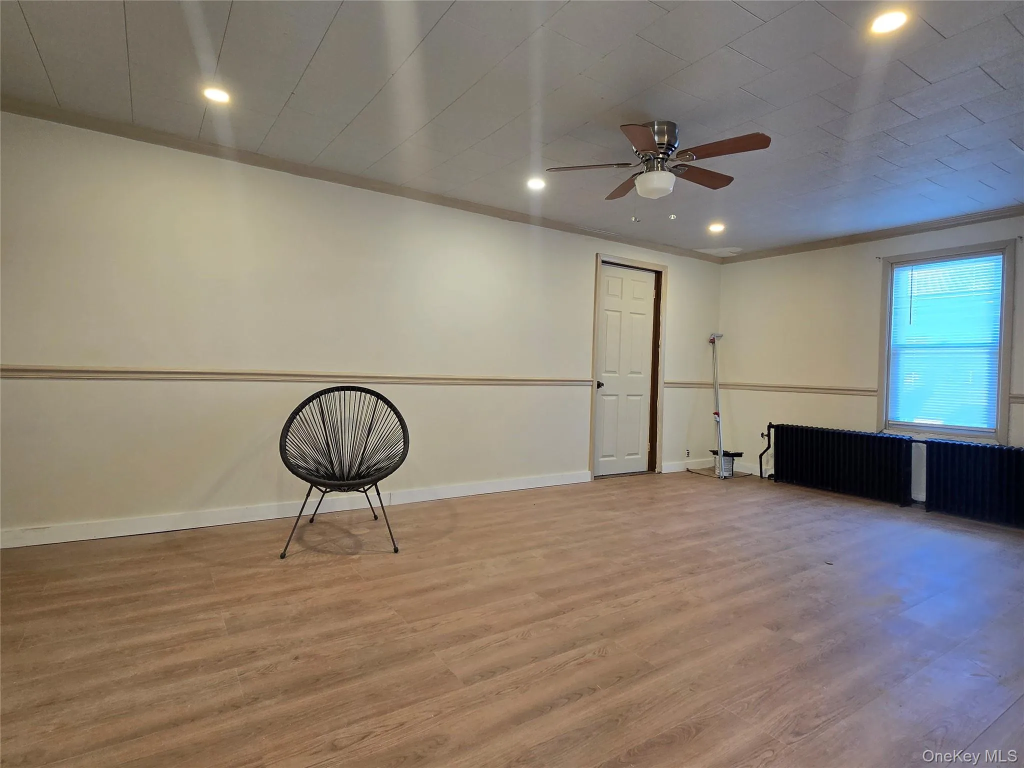 Spare room with radiator heating unit, wood finished floors, a ceiling fan, recessed lighting, and crown molding Spare room with radiator heating unit, wood finished floors, a ceiling fan, recessed lighting, and crown molding