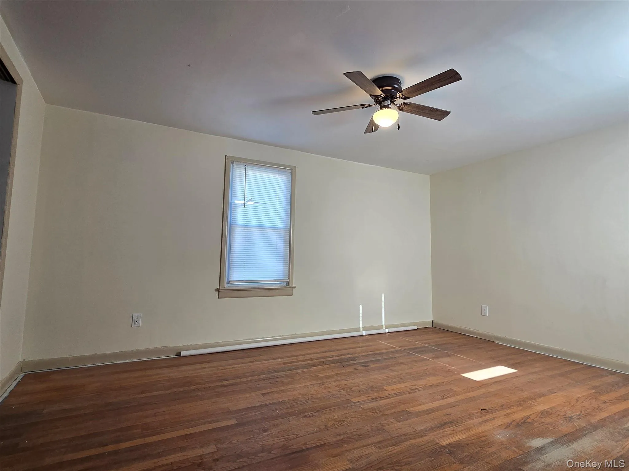 Unfurnished room featuring dark wood-style flooring and a ceiling fan Unfurnished room featuring dark wood-style flooring and a ceiling fan