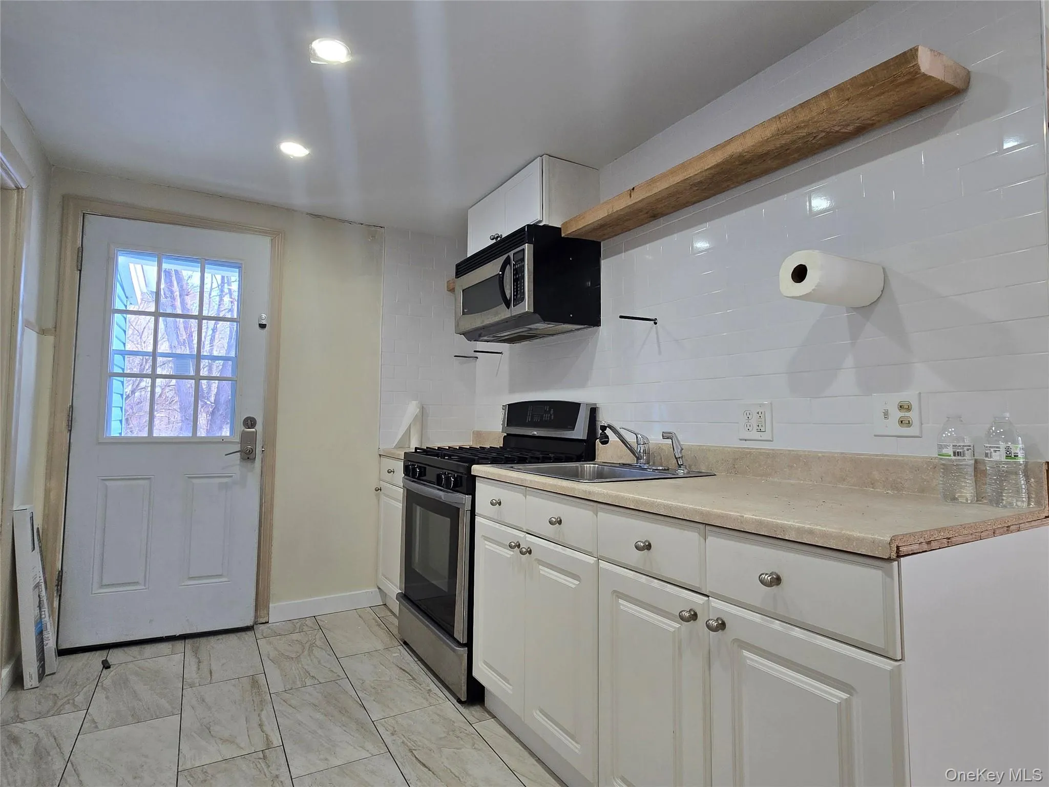Kitchen featuring white cabinets, stainless steel appliances, open shelves, light countertops, and recessed lighting Kitchen featuring white cabinets, stainless steel appliances, open shelves, light countertops, and recessed lighting