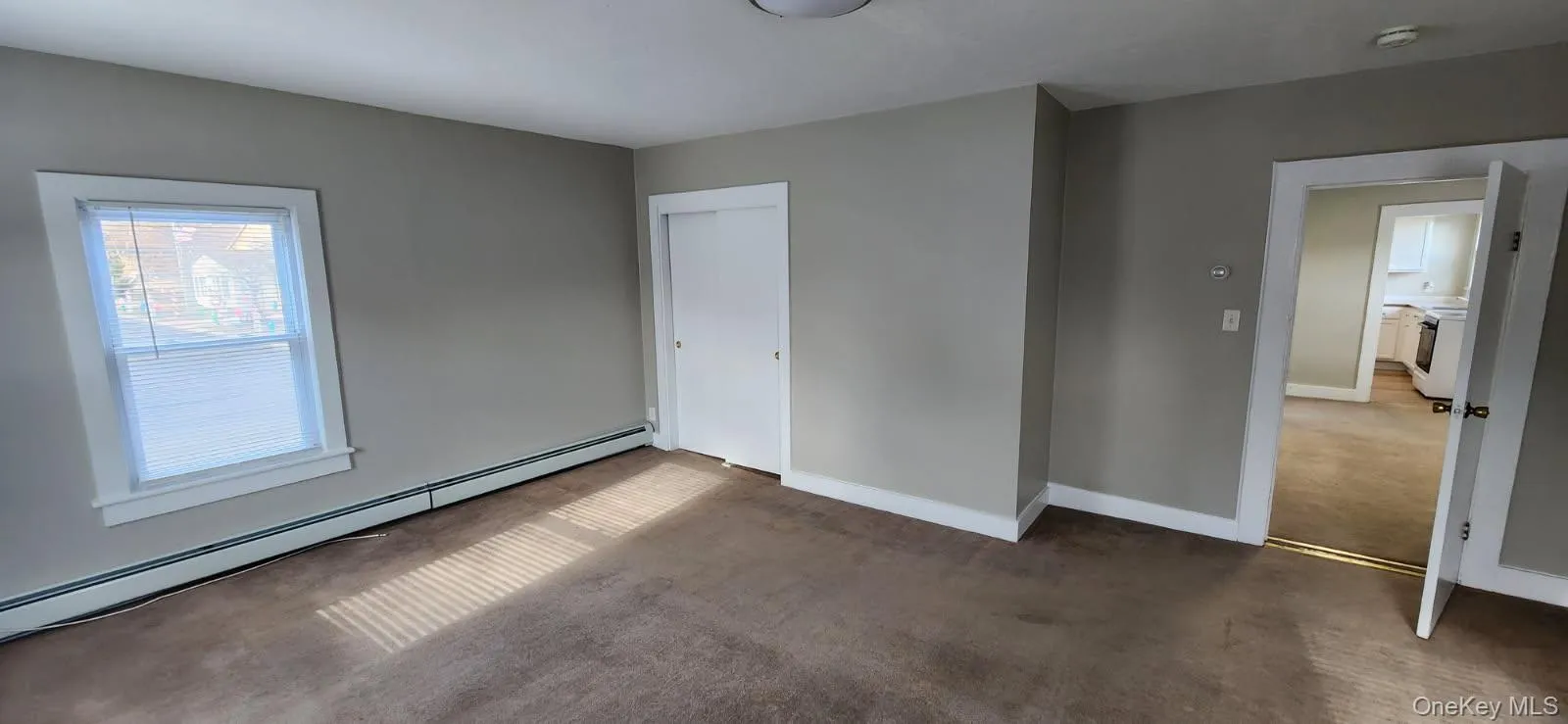 Unfurnished bedroom featuring baseboard heating, a closet, and carpet floors Unfurnished bedroom featuring baseboard heating, a closet, and carpet floors