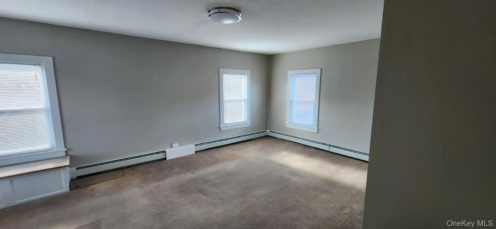 Unfurnished room featuring baseboard heating and carpet flooring Unfurnished room featuring baseboard heating and carpet flooring