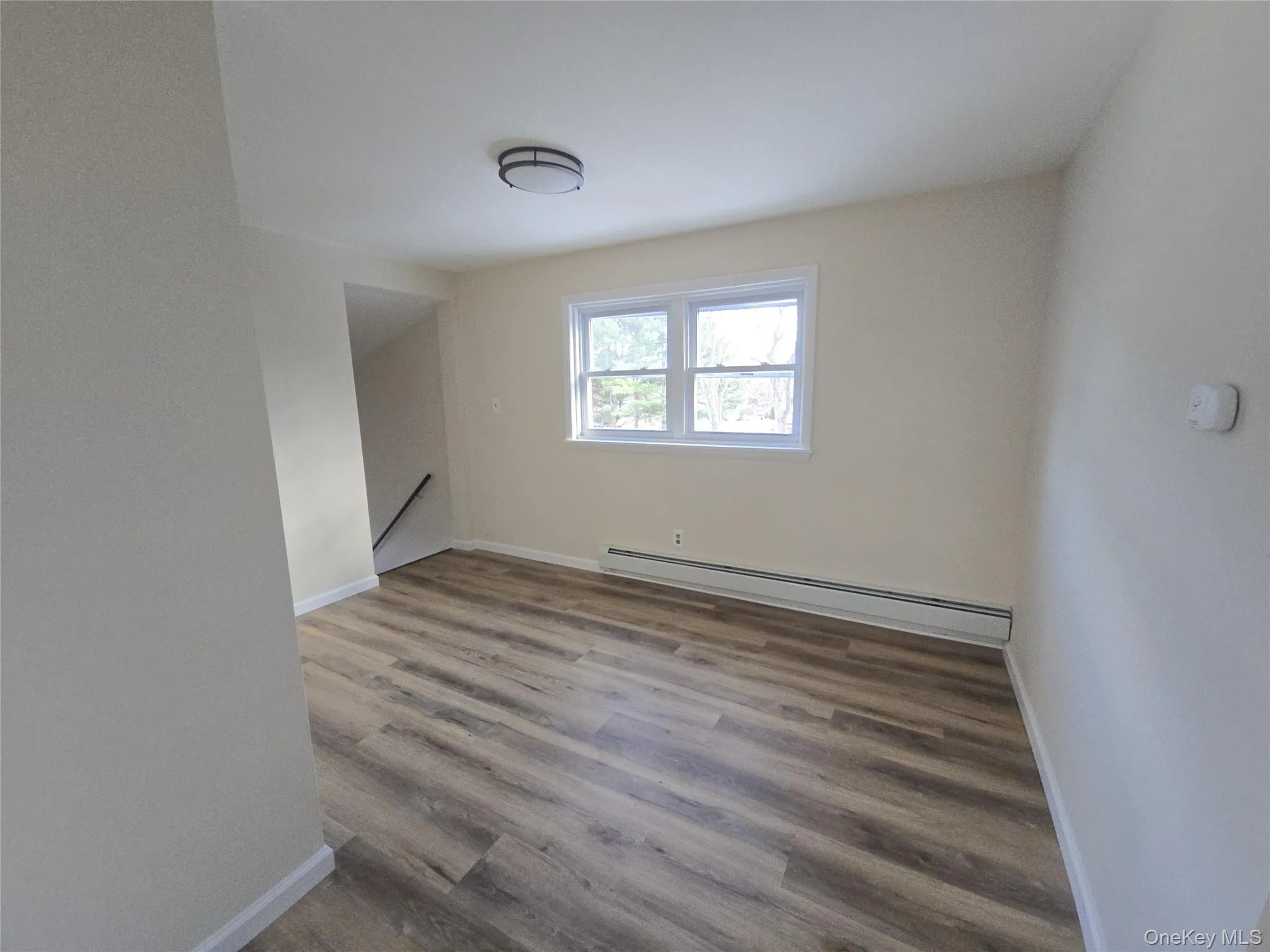Empty room with a baseboard radiator and wood finished floors Empty room with a baseboard radiator and wood finished floors