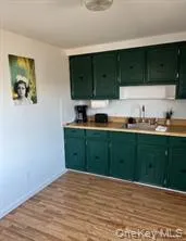 Kitchen featuring green cabinets, light countertops, and dark wood-style flooring Kitchen featuring green cabinets, light countertops, and dark wood-style flooring