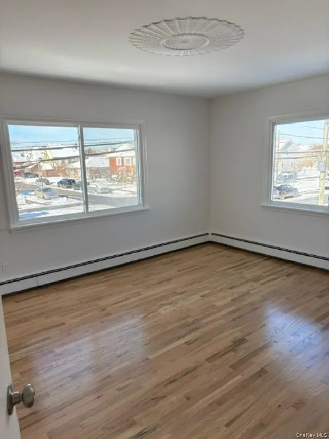 Spare room with a baseboard heating unit and light wood-style floors Spare room with a baseboard heating unit and light wood-style floors