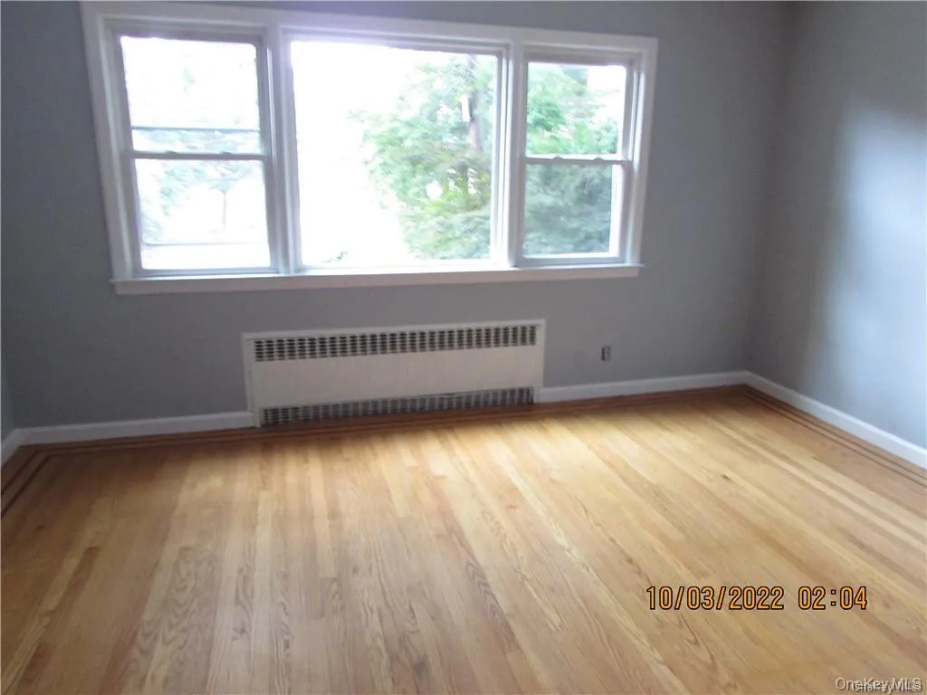 Spare room featuring radiator heating unit and light wood finished floors Spare room featuring radiator heating unit and light wood finished floors
