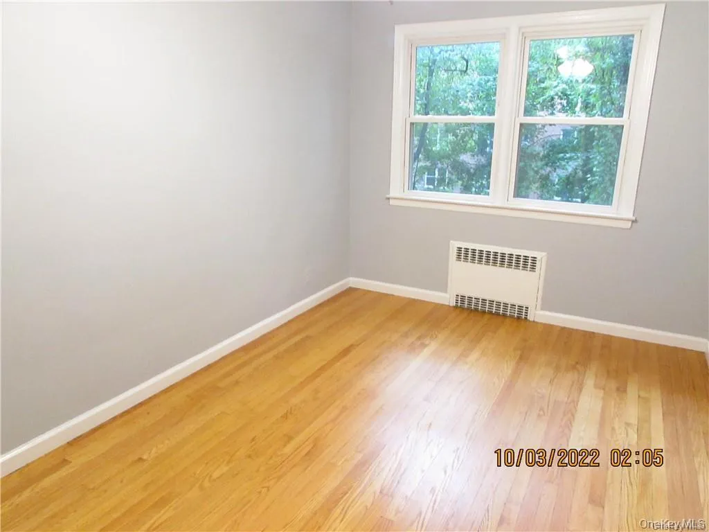 Empty room featuring radiator heating unit and light wood finished floors Empty room featuring radiator heating unit and light wood finished floors