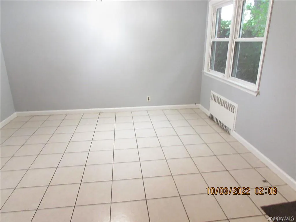 Empty room featuring radiator heating unit and light tile patterned flooring Empty room featuring radiator heating unit and light tile patterned flooring