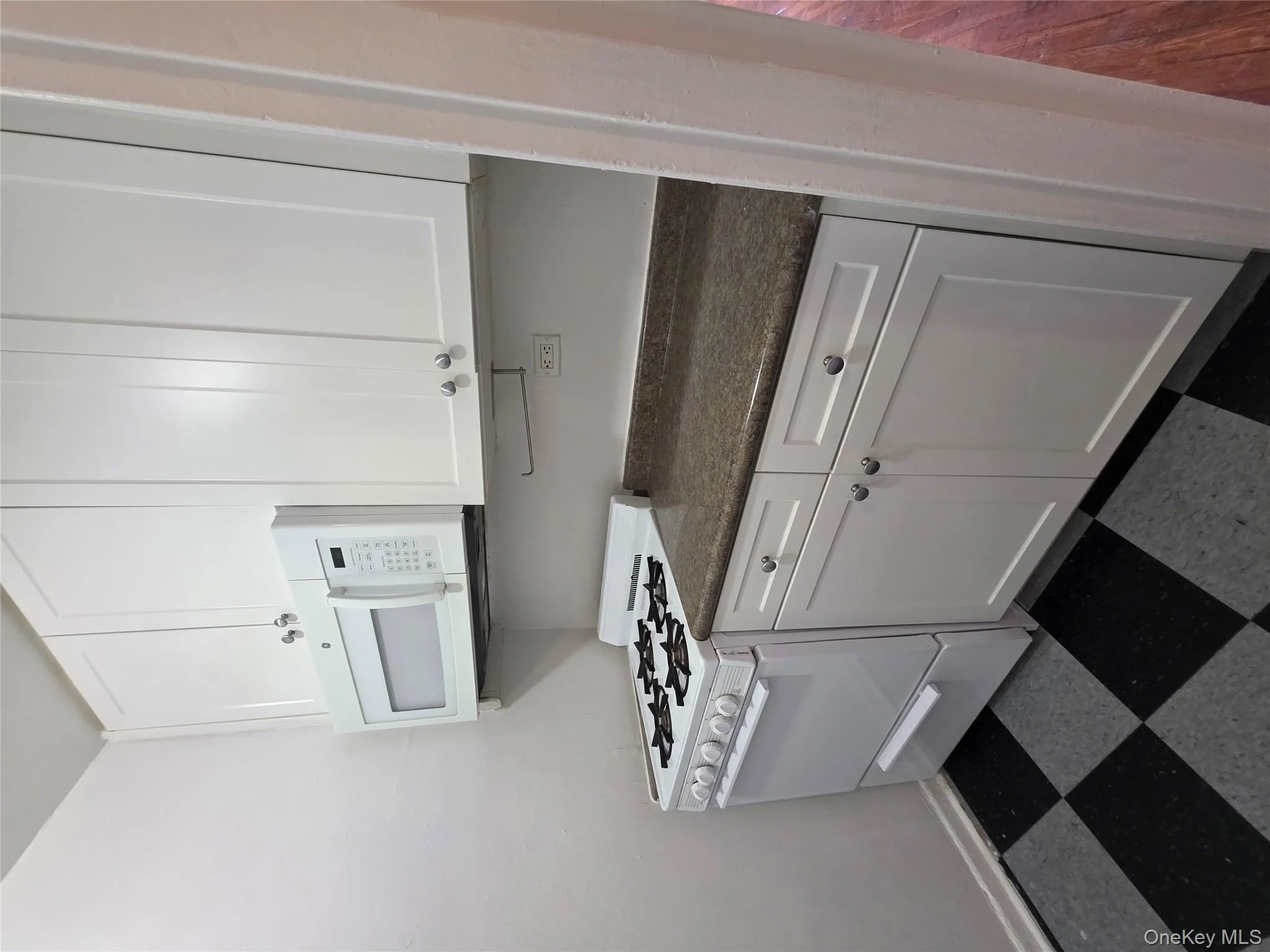 Kitchen with white stove, dark countertops, white cabinetry, and dark flooring Kitchen with white stove, dark countertops, white cabinetry, and dark flooring