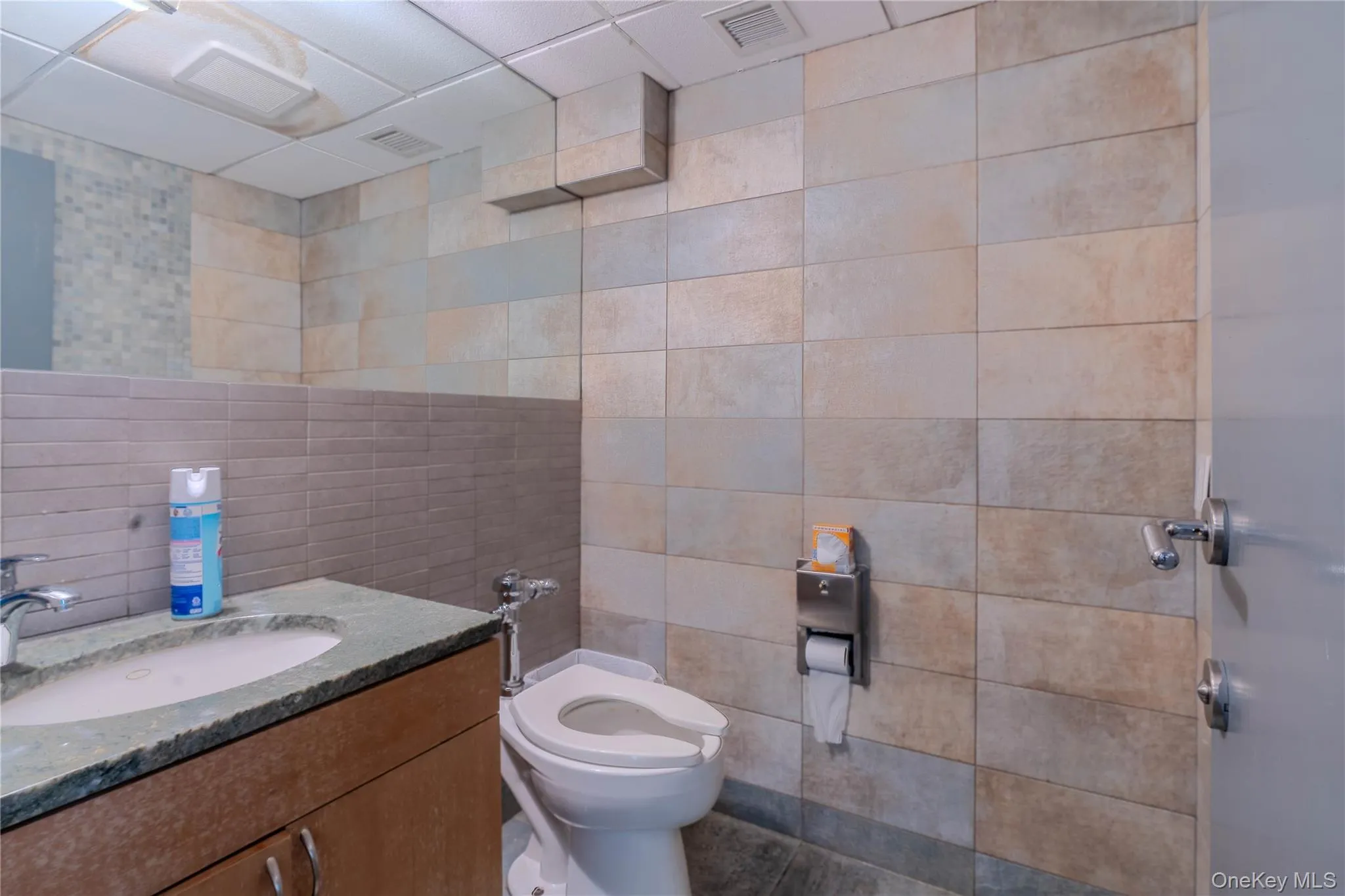 Bathroom featuring tile walls, vanity, and a paneled ceiling Bathroom featuring tile walls, vanity, and a paneled ceiling