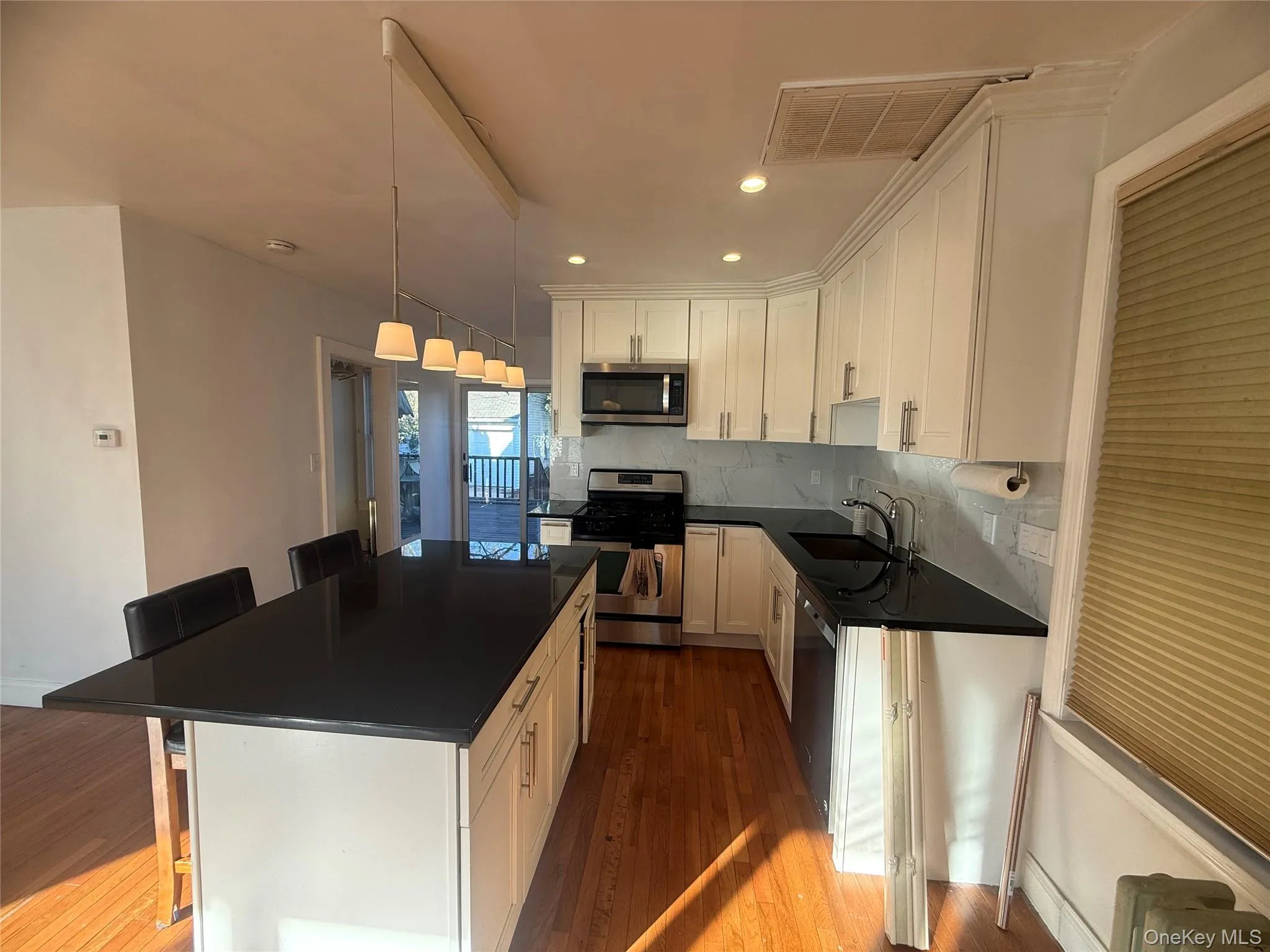 Kitchen featuring a breakfast bar, stainless steel appliances, a kitchen island, tasteful backsplash, and light wood finished floors Kitchen featuring a breakfast bar, stainless steel appliances, a kitchen island, tasteful backsplash, and light wood finished floors