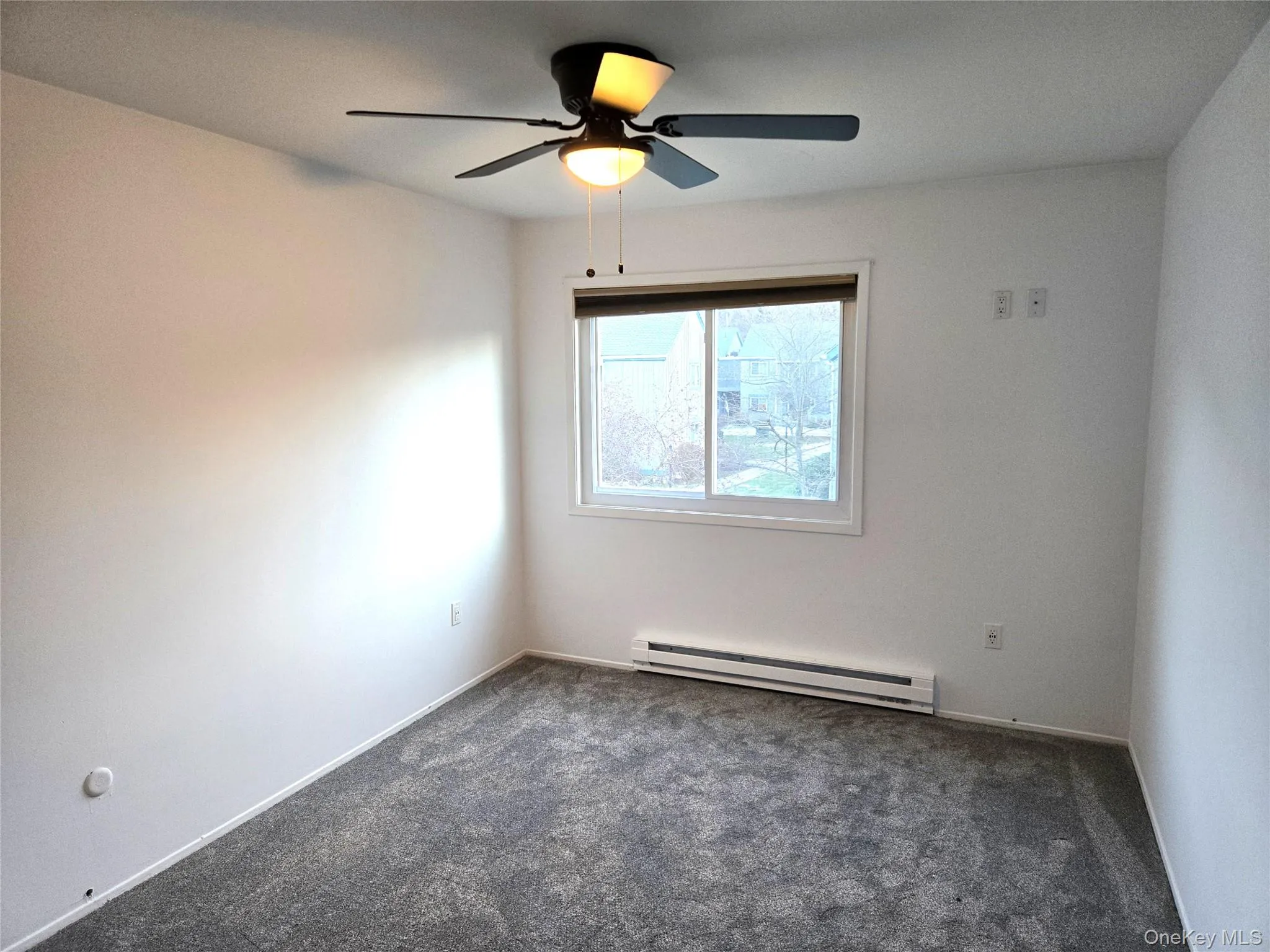 Carpeted spare room featuring baseboard heating and a ceiling fan Carpeted spare room featuring baseboard heating and a ceiling fan