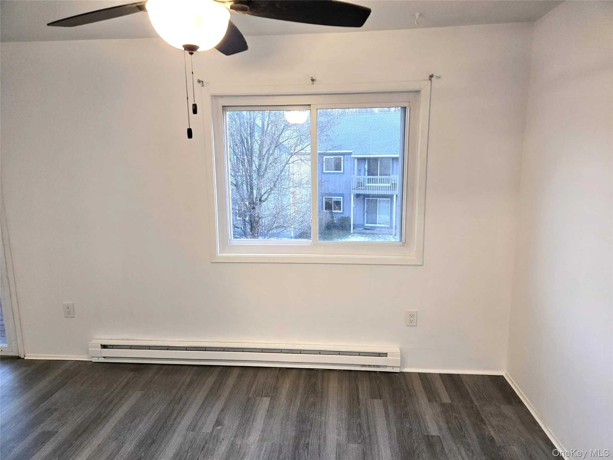 Spare room with dark wood-style flooring, ceiling fan, and a baseboard radiator Spare room with dark wood-style flooring, ceiling fan, and a baseboard radiator