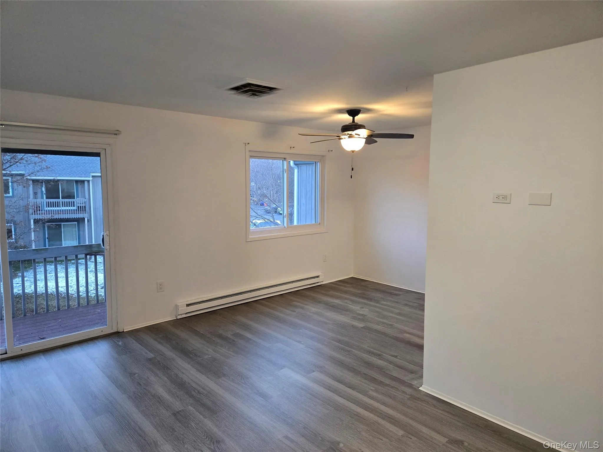 Unfurnished room featuring a baseboard radiator, dark wood-style flooring, and a ceiling fan Unfurnished room featuring a baseboard radiator, dark wood-style flooring, and a ceiling fan