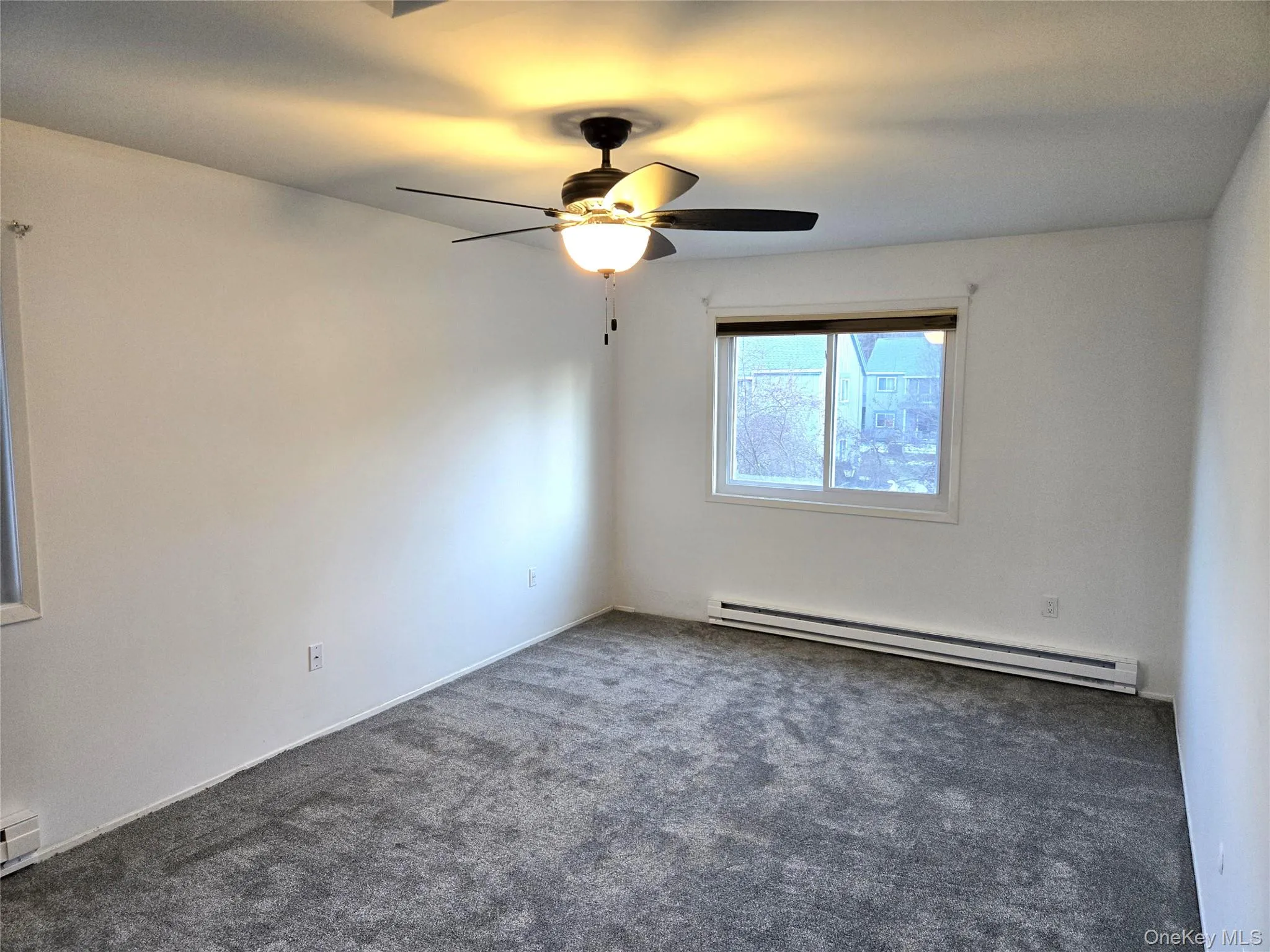 Unfurnished room featuring a baseboard heating unit, carpet, and ceiling fan Unfurnished room featuring a baseboard heating unit, carpet, and ceiling fan