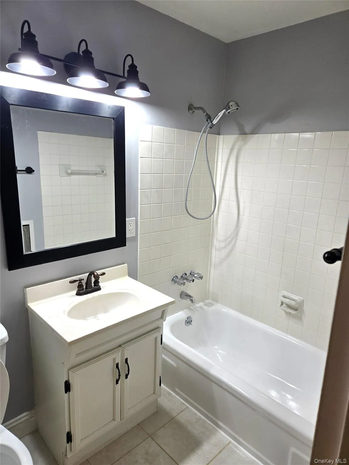 Full bath with bathtub / shower combination, vanity, and light tile patterned floors Full bath with bathtub / shower combination, vanity, and light tile patterned floors