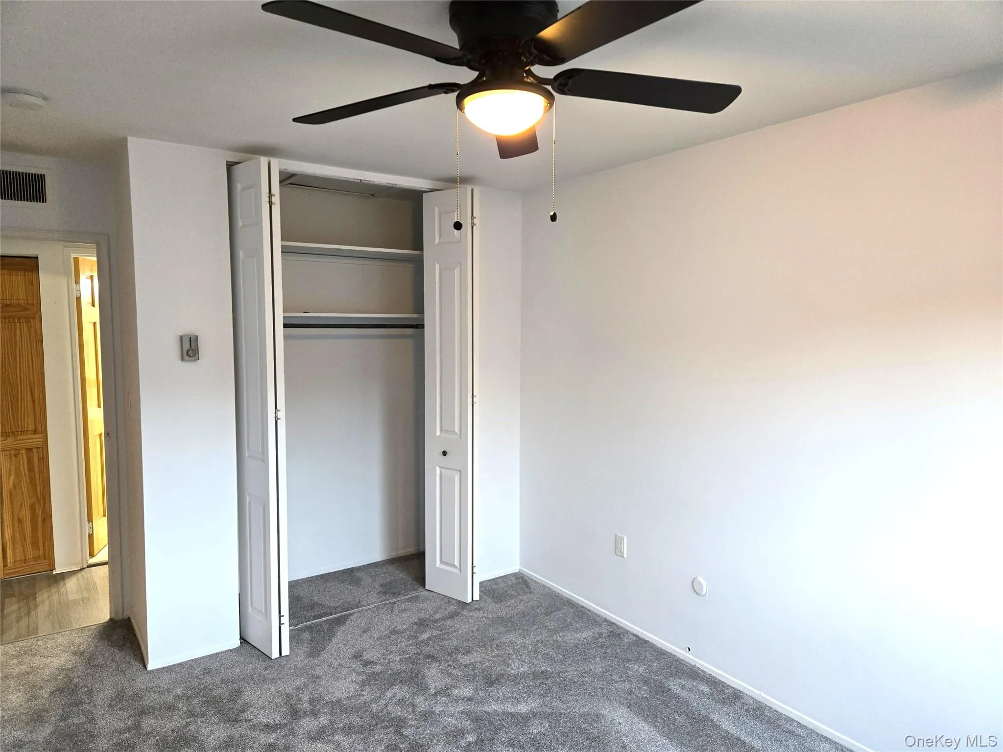 Unfurnished bedroom featuring dark carpet, a ceiling fan, and a closet Unfurnished bedroom featuring dark carpet, a ceiling fan, and a closet