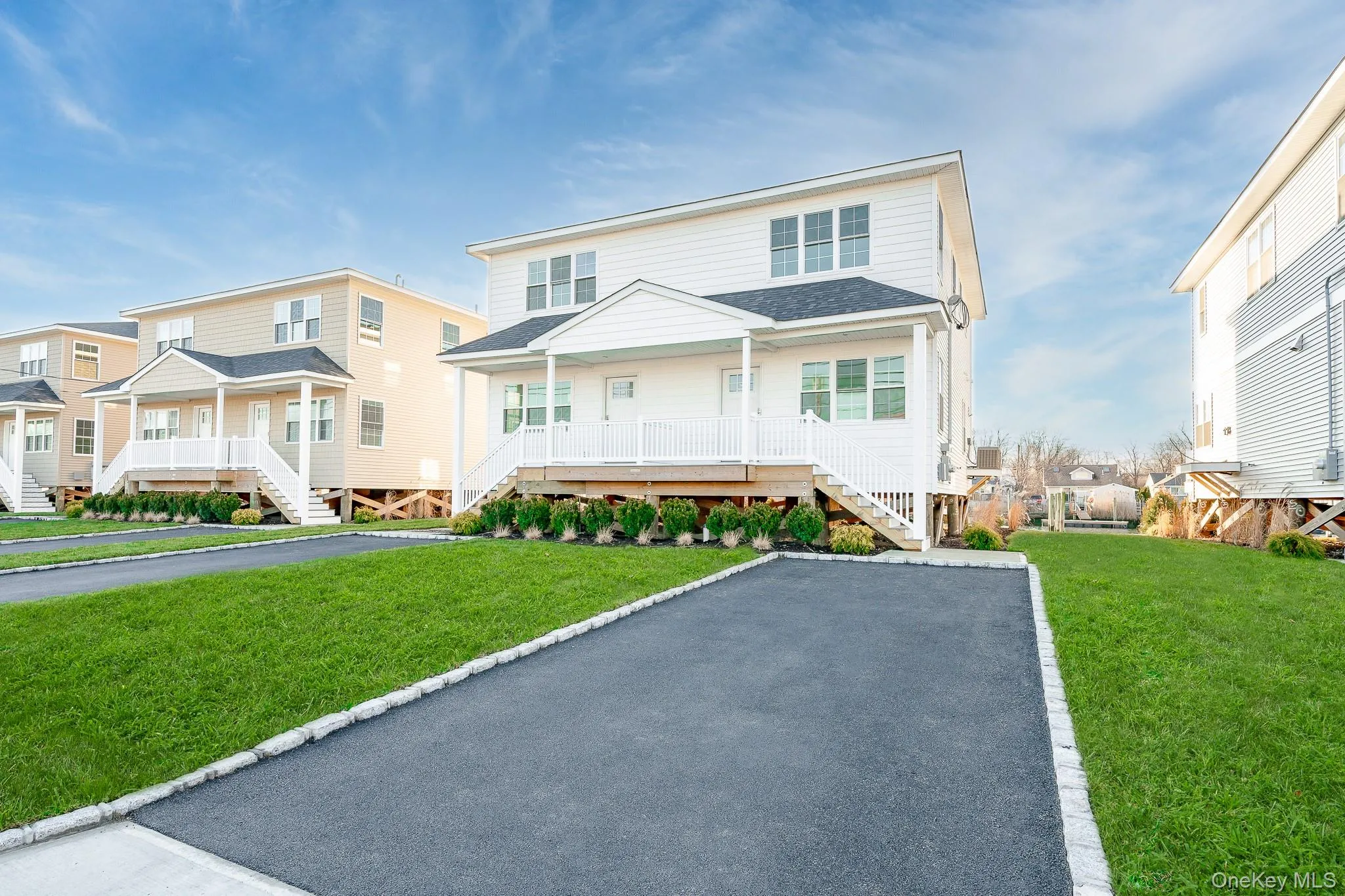 View of front facade with a shingled roof, a front lawn, stairway, and a porch View of front facade with a shingled roof, a front lawn, stairway, and a porch