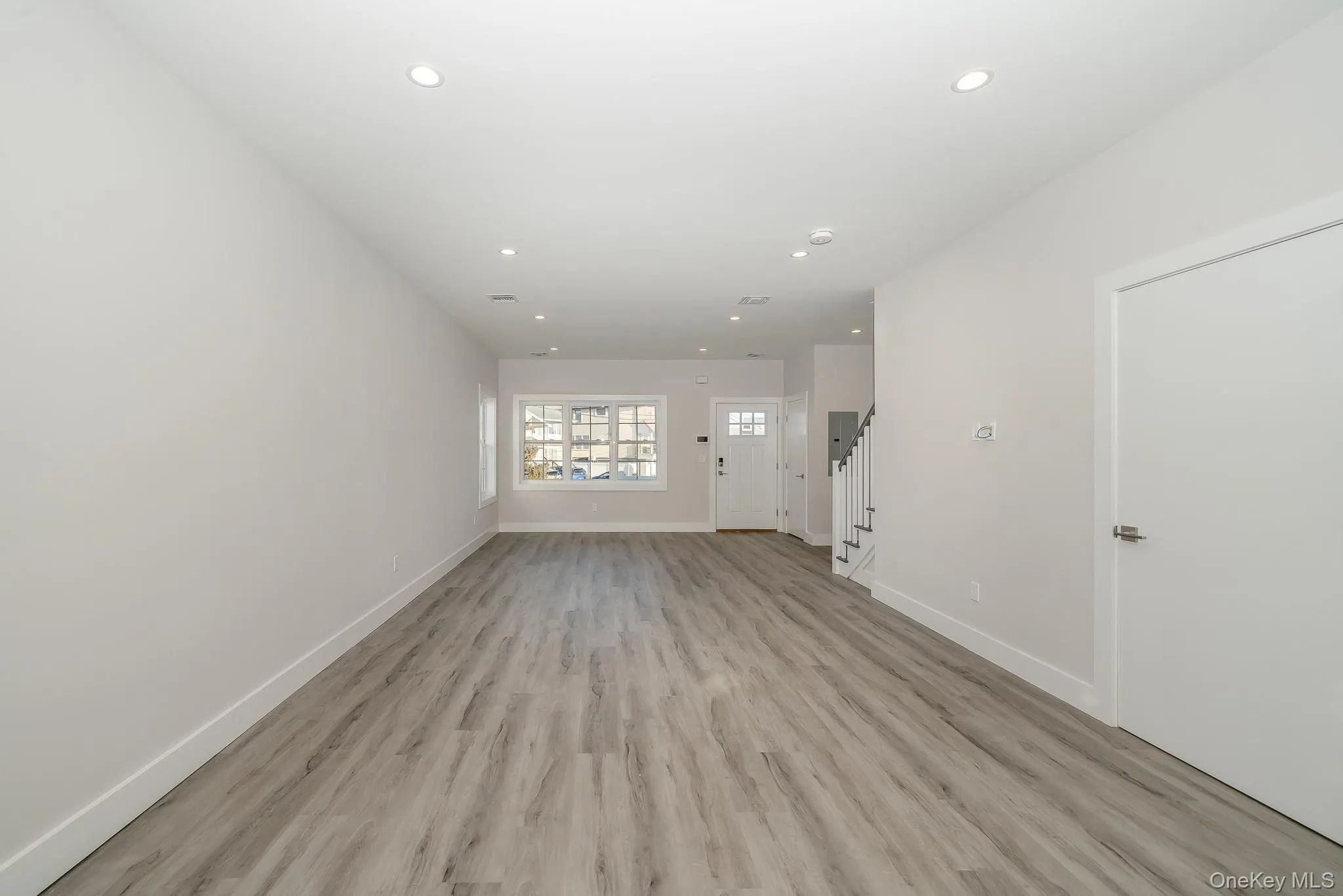 Unfurnished living room featuring light wood-style floors, recessed lighting, and stairway Unfurnished living room featuring light wood-style floors, recessed lighting, and stairway