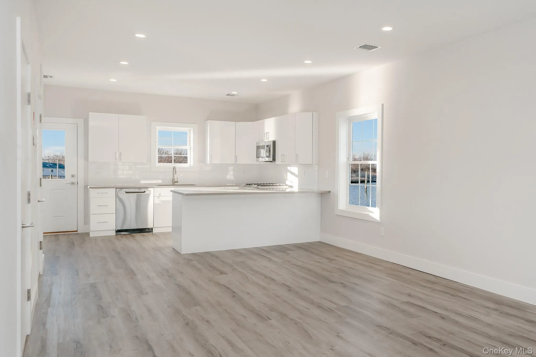 Kitchen with white cabinetry, a peninsula, light countertops, tasteful backsplash, and appliances with stainless steel finishes Kitchen with white cabinetry, a peninsula, light countertops, tasteful backsplash, and appliances with stainless steel finishes