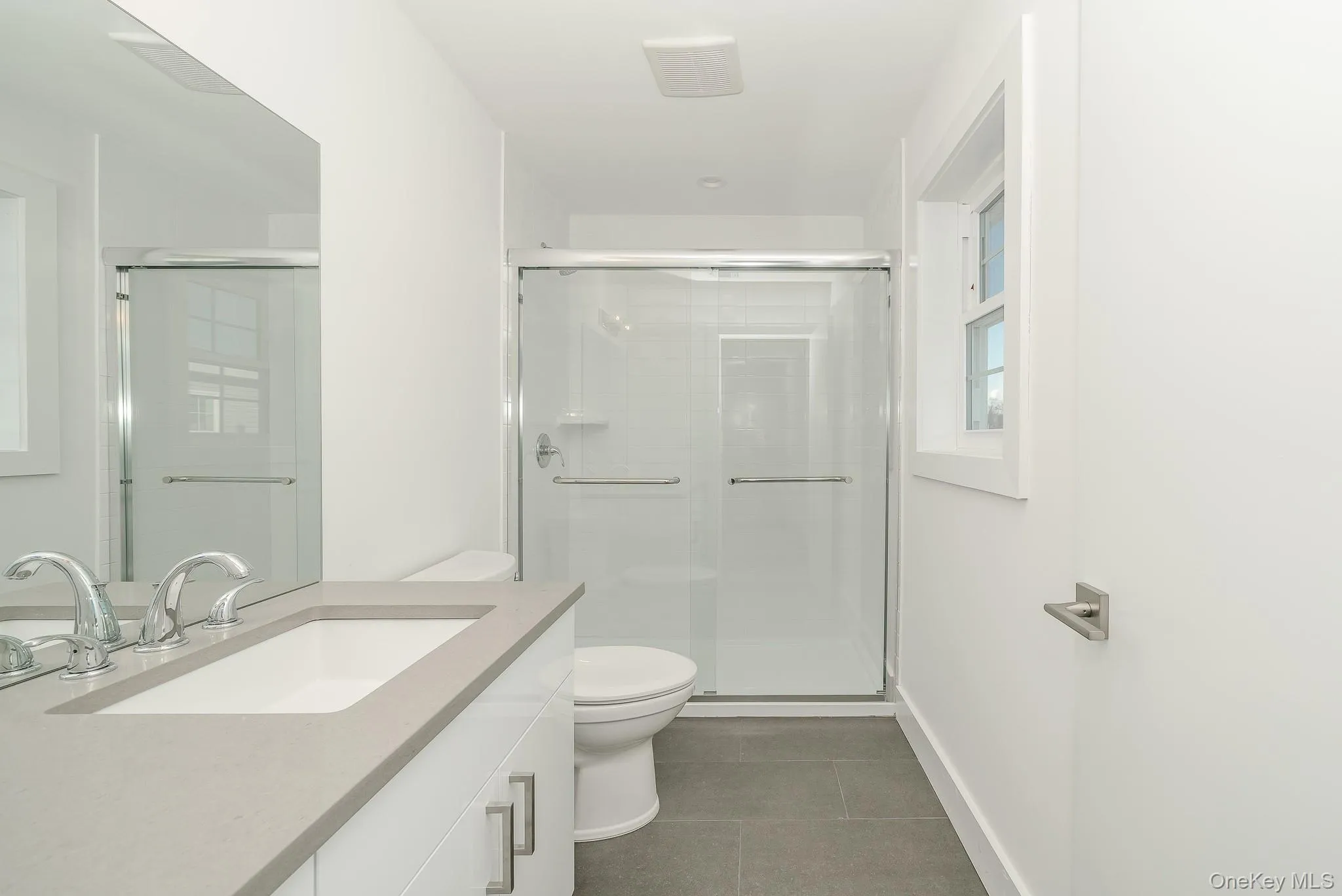 Bathroom with vanity, a shower stall, and dark tile patterned flooring Bathroom with vanity, a shower stall, and dark tile patterned flooring