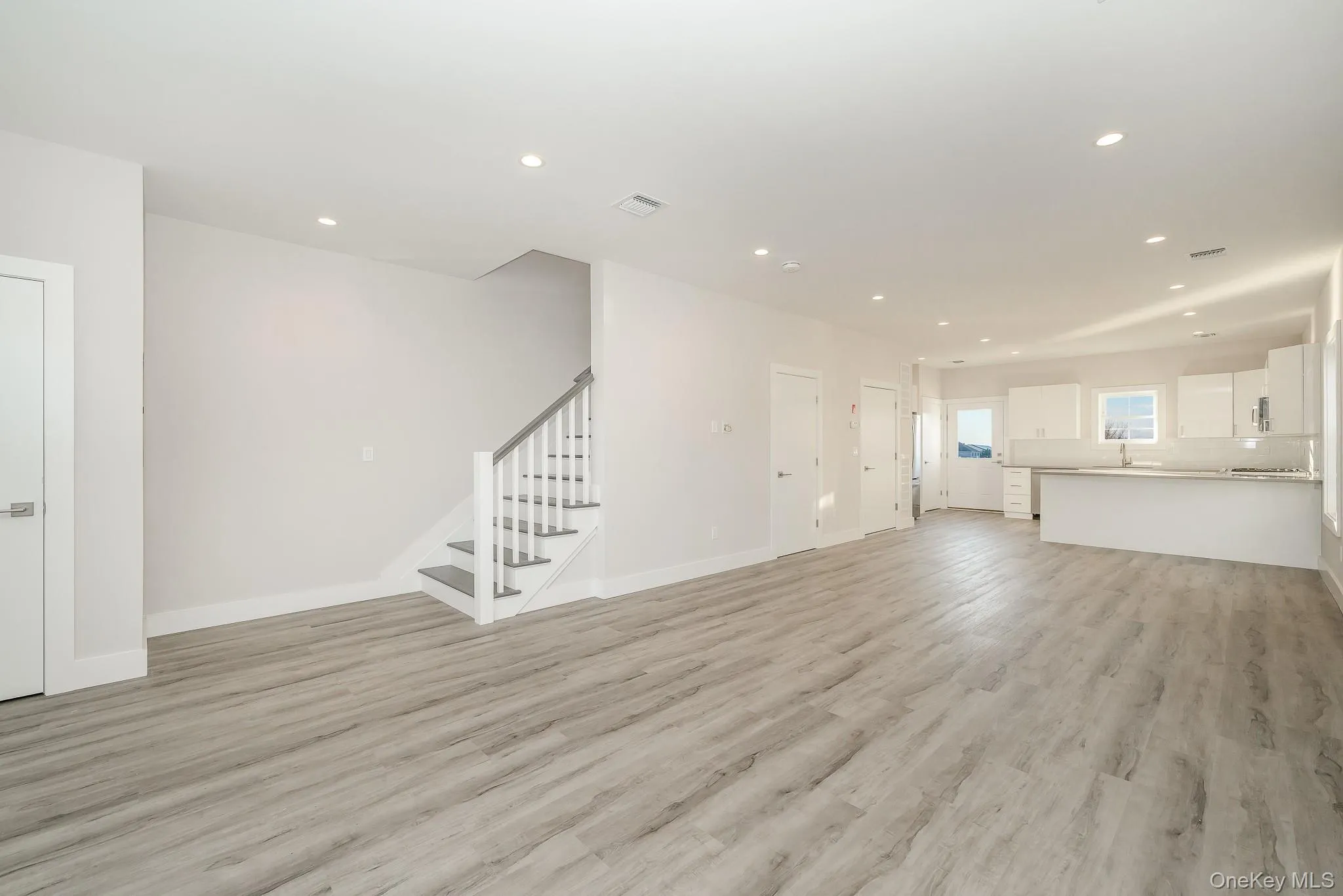 Unfurnished living room with stairway, recessed lighting, and light wood-style floors Unfurnished living room with stairway, recessed lighting, and light wood-style floors
