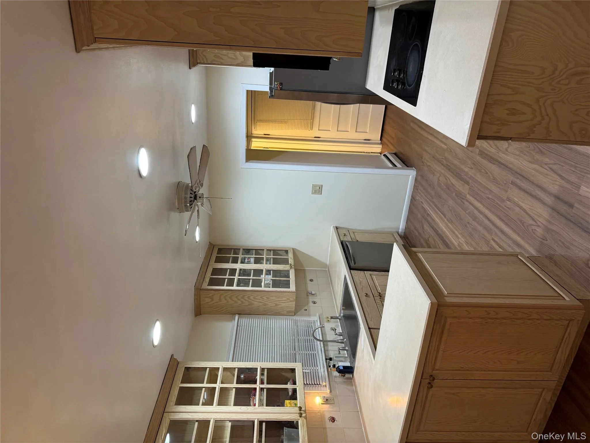 Kitchen with backsplash, a peninsula, light countertops, glass insert cabinets, and cooktop Kitchen with backsplash, a peninsula, light countertops, glass insert cabinets, and cooktop