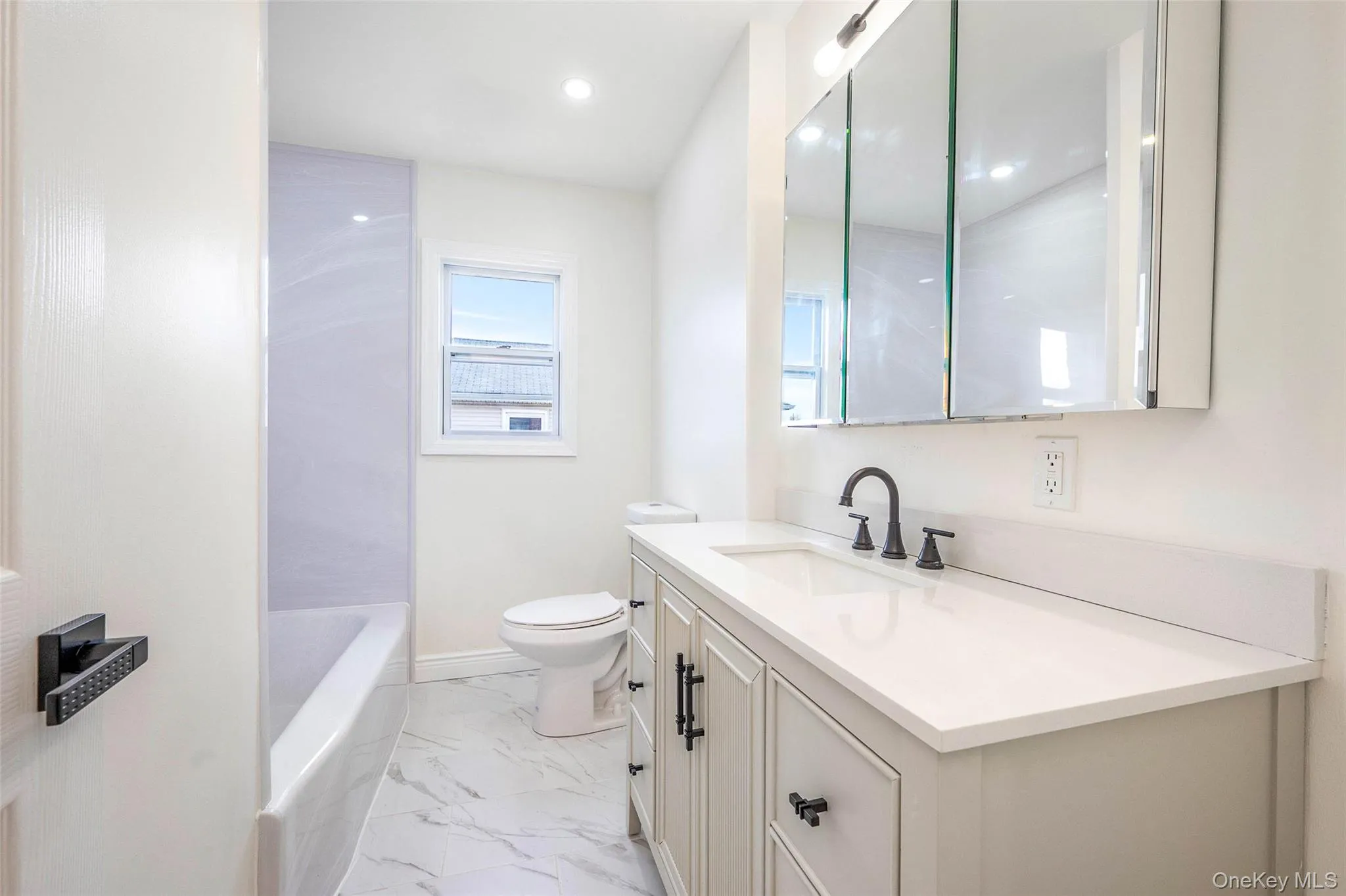 Bathroom featuring vanity, light marble finish floors, recessed lighting, and bathtub / shower combination Bathroom featuring vanity, light marble finish floors, recessed lighting, and bathtub / shower combination