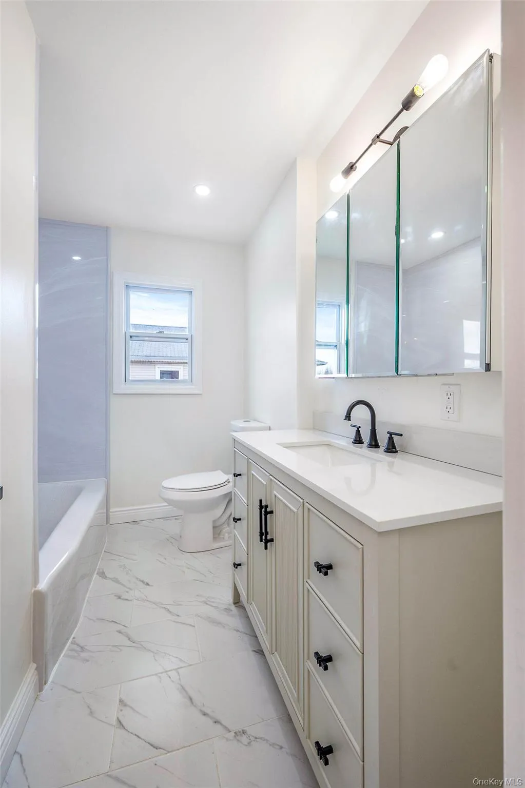 Bathroom featuring vanity, light marble finish floors, and shower / bath combination Bathroom featuring vanity, light marble finish floors, and shower / bath combination