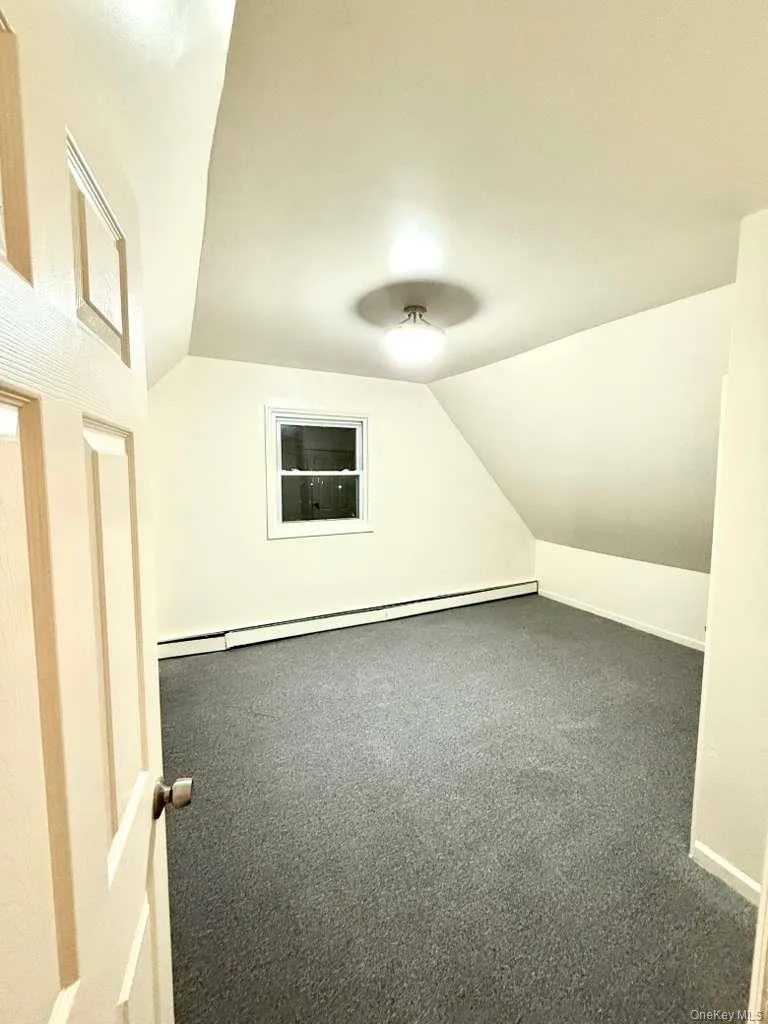 Bonus room with vaulted ceiling, a baseboard radiator, and carpet floors Bonus room with vaulted ceiling, a baseboard radiator, and carpet floors