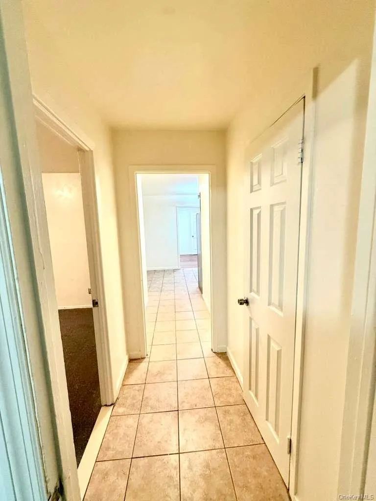 Hallway with light tile patterned floors and baseboards Hallway with light tile patterned floors and baseboards