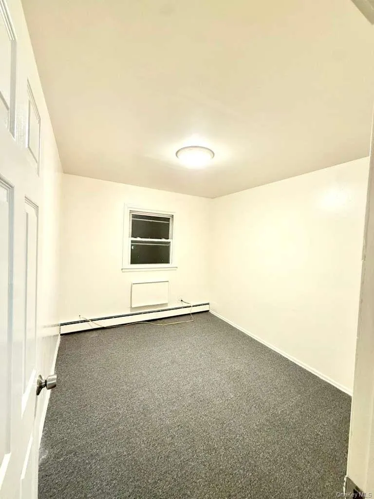 Empty room featuring carpet and a baseboard heating unit Empty room featuring carpet and a baseboard heating unit