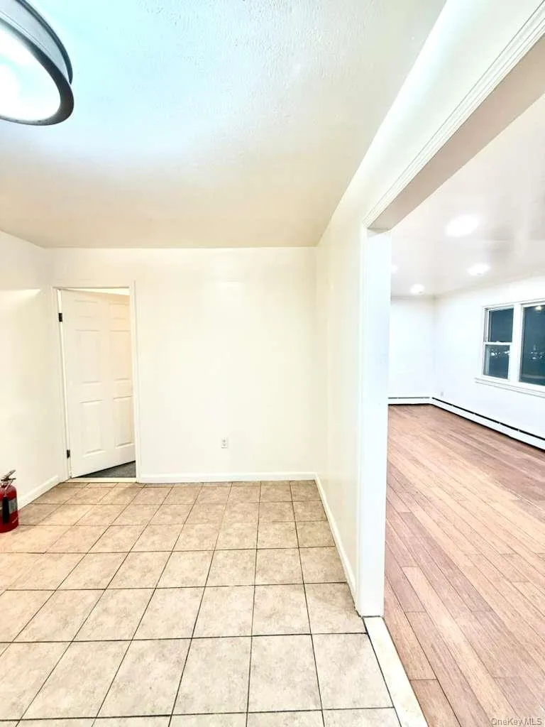 Unfurnished room with light tile patterned floors and a baseboard radiator Unfurnished room with light tile patterned floors and a baseboard radiator