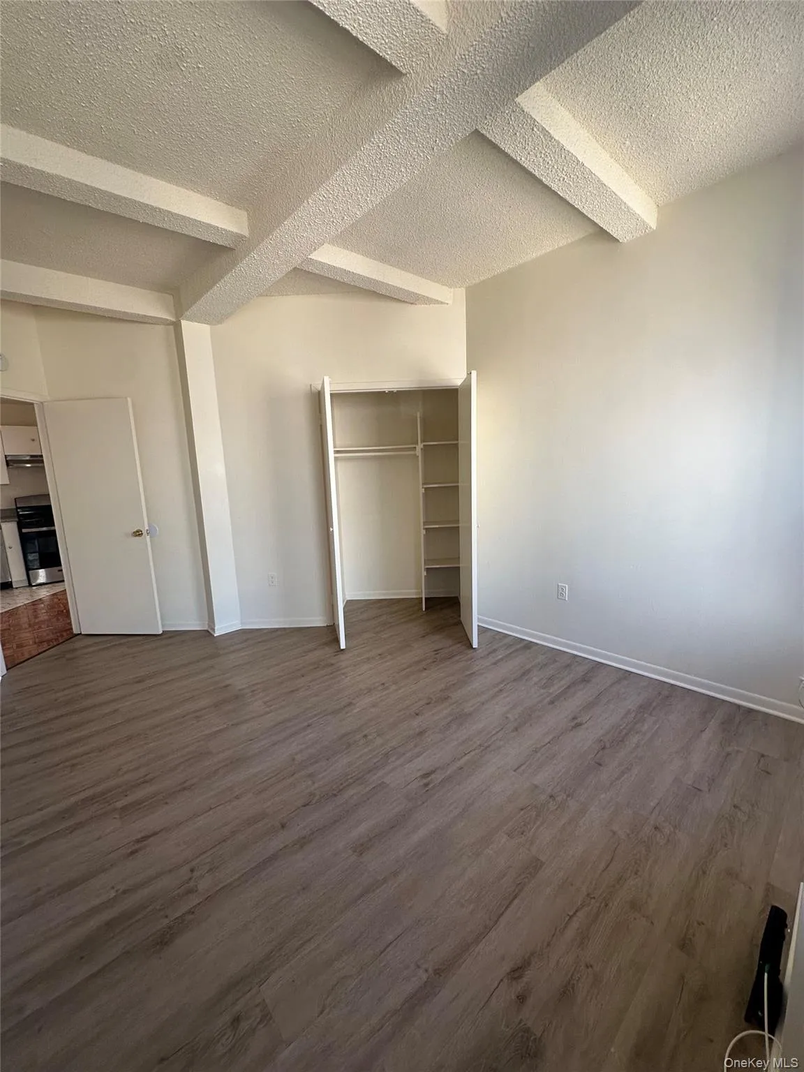 Unfurnished bedroom with a textured ceiling, wood finished floors, and a closet Unfurnished bedroom with a textured ceiling, wood finished floors, and a closet