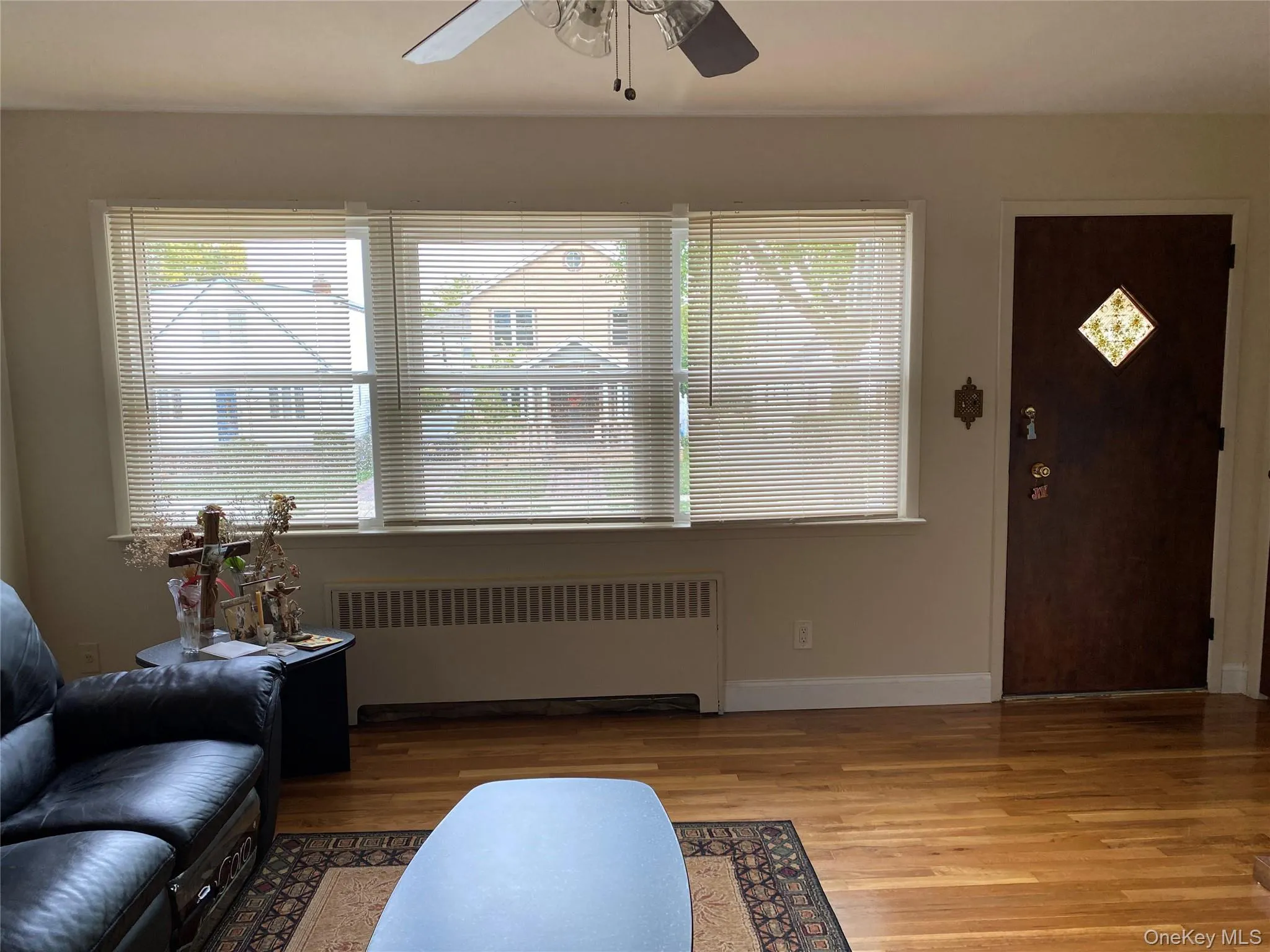 Entrance foyer with radiator heating unit, wood finished floors, and a ceiling fan Entrance foyer with radiator heating unit, wood finished floors, and a ceiling fan