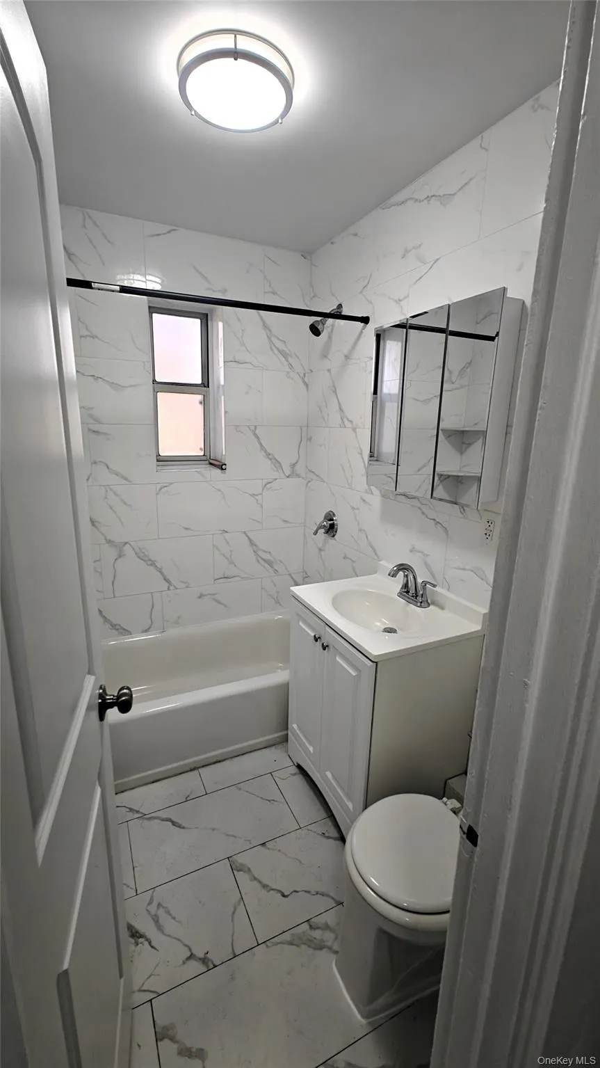 Full bath featuring light marble finish flooring, vanity, and shower / washtub combination Full bath featuring light marble finish flooring, vanity, and shower / washtub combination